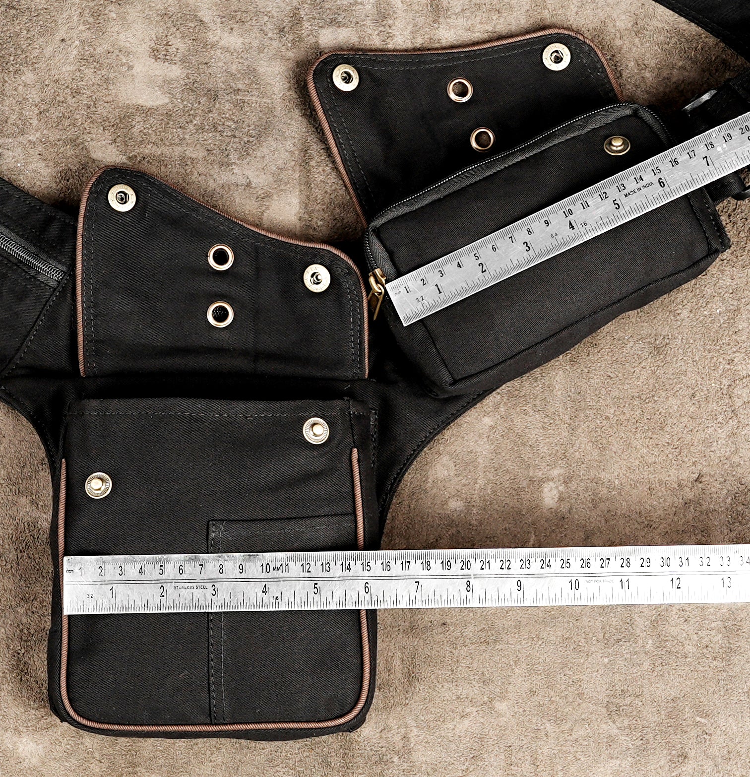Black fanny pack with brass zippers and brown piped edges