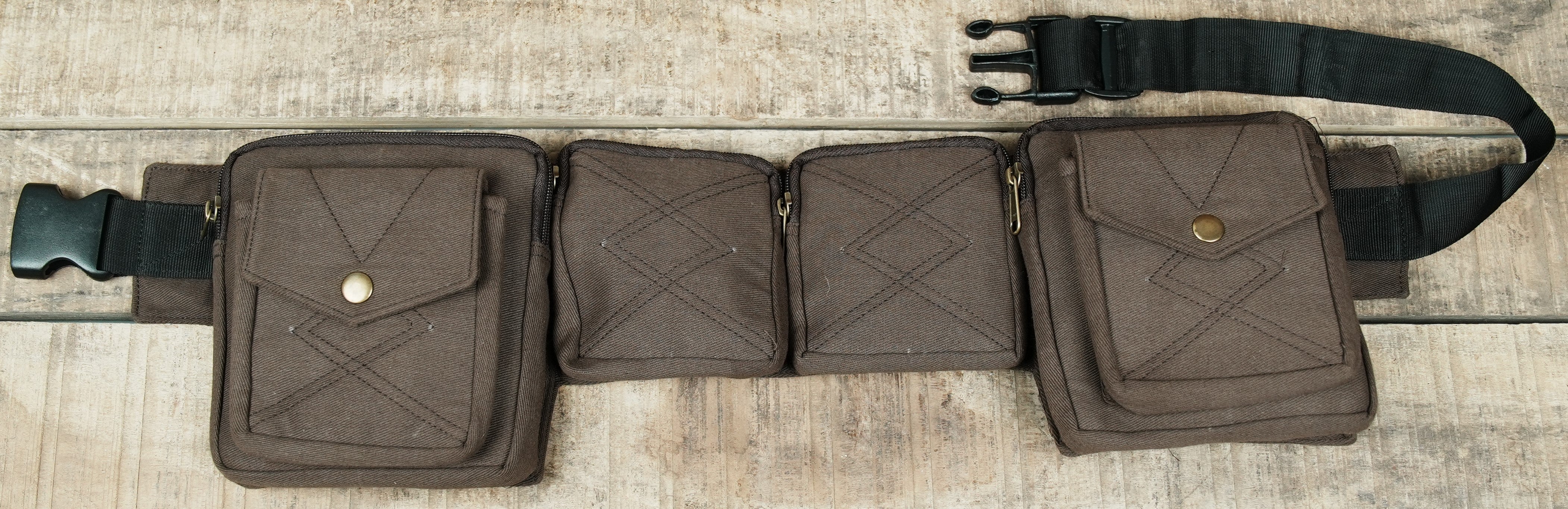 Multi-compartment cotton fanny pack in black laid open on rustic wood background