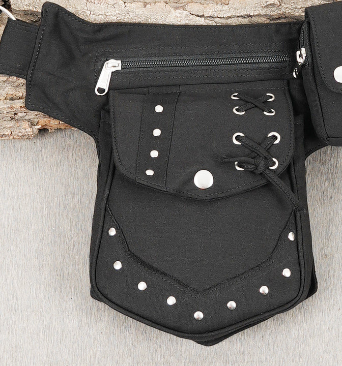 Alternative style hip belt bag with unique lacing and zippered compartments, laid flat.