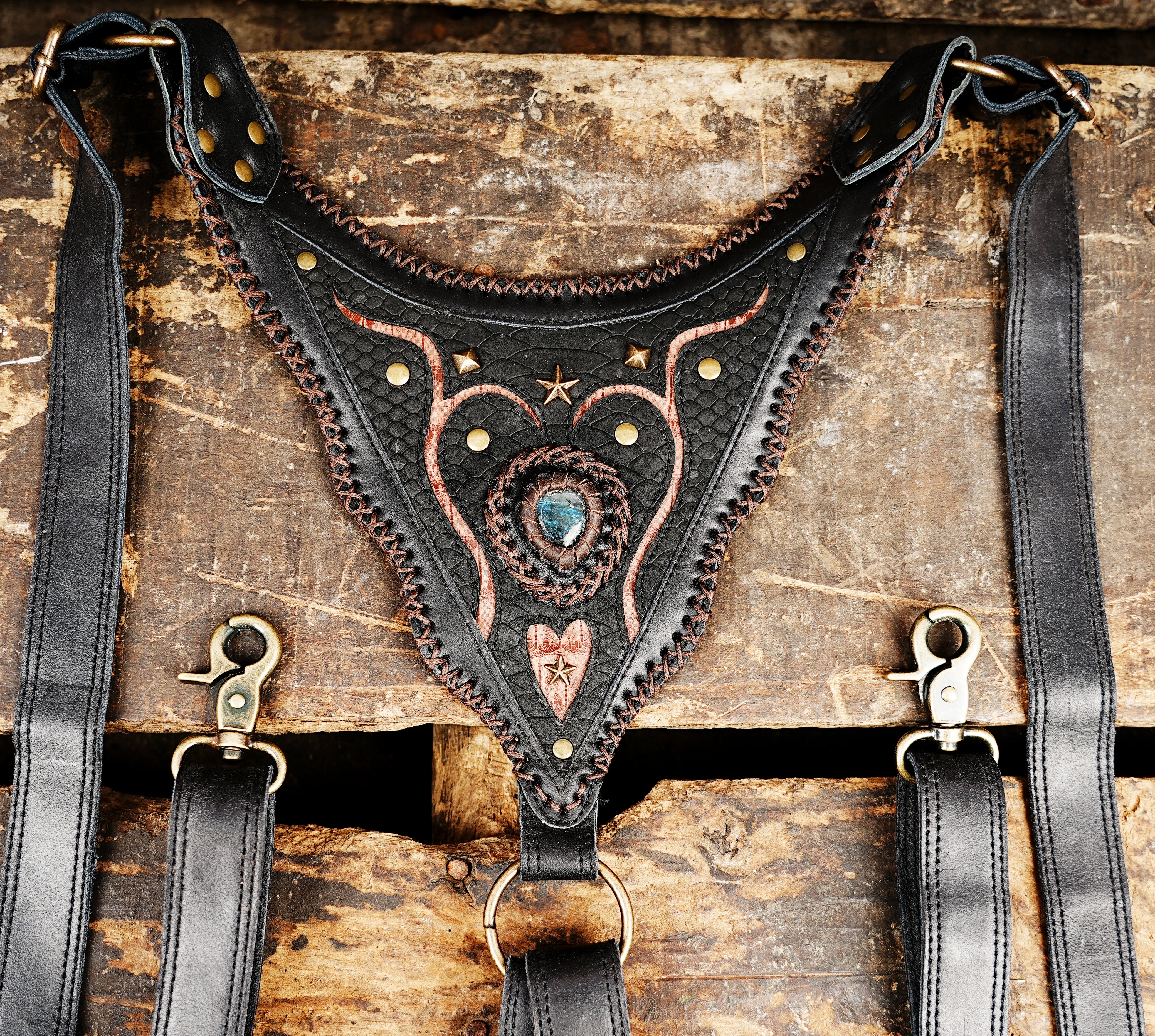 “Black tribal-style leather holster with copper inlays and teardrop stone design”