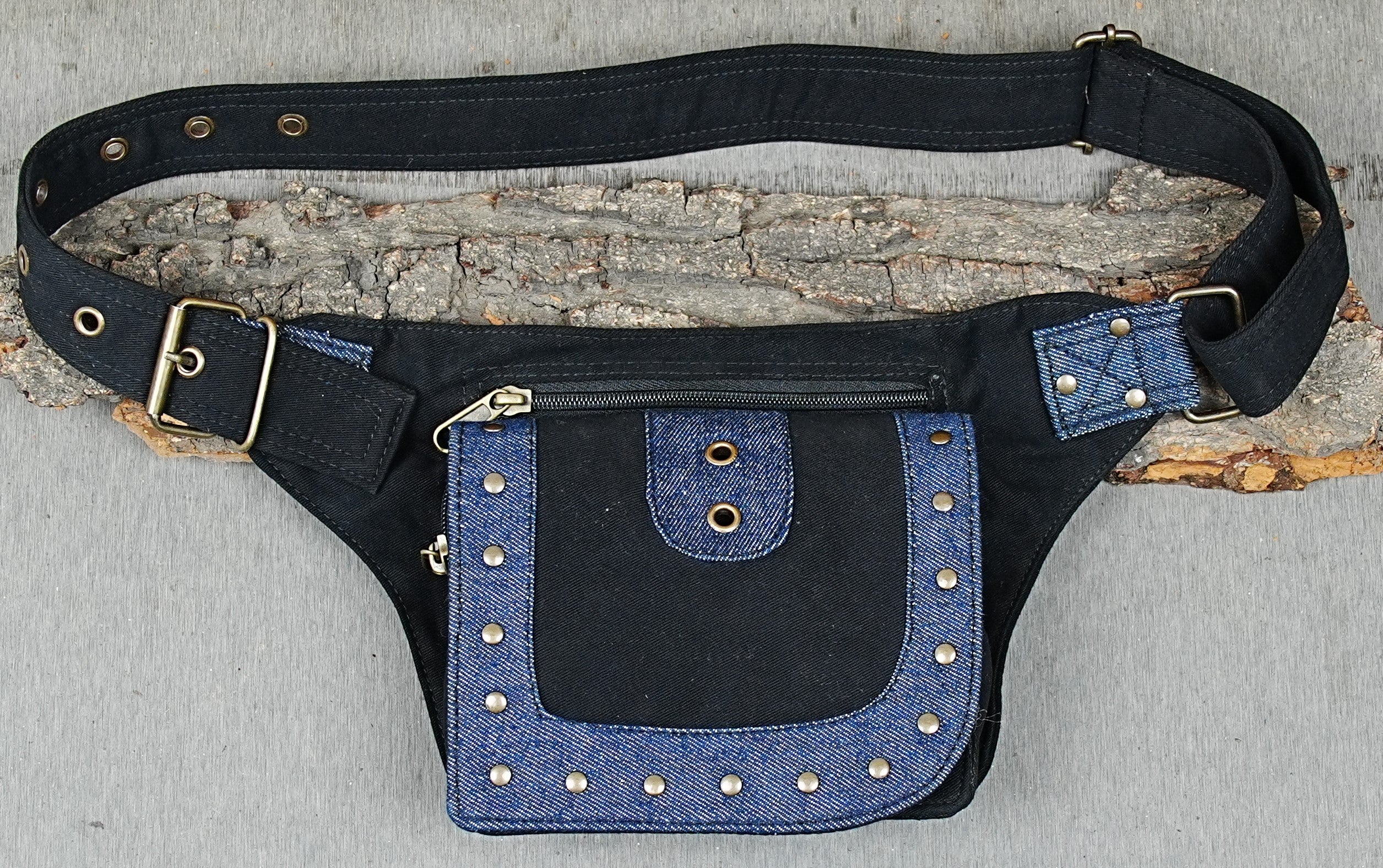 Handmade black canvas utility belt with studded blue denim trim laid flat