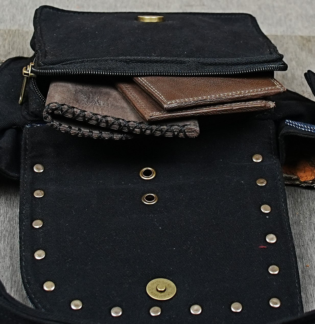 Unisex canvas hip pack with brass hardware laid out on textured background