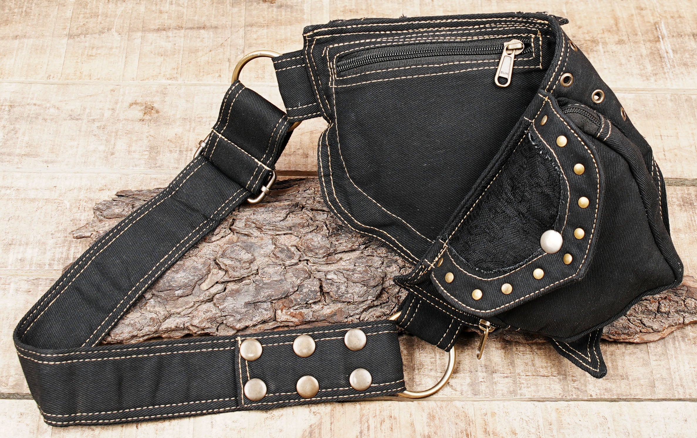 Bohemian festival waist pack with metal eyelet center band laid flat on rustic wood