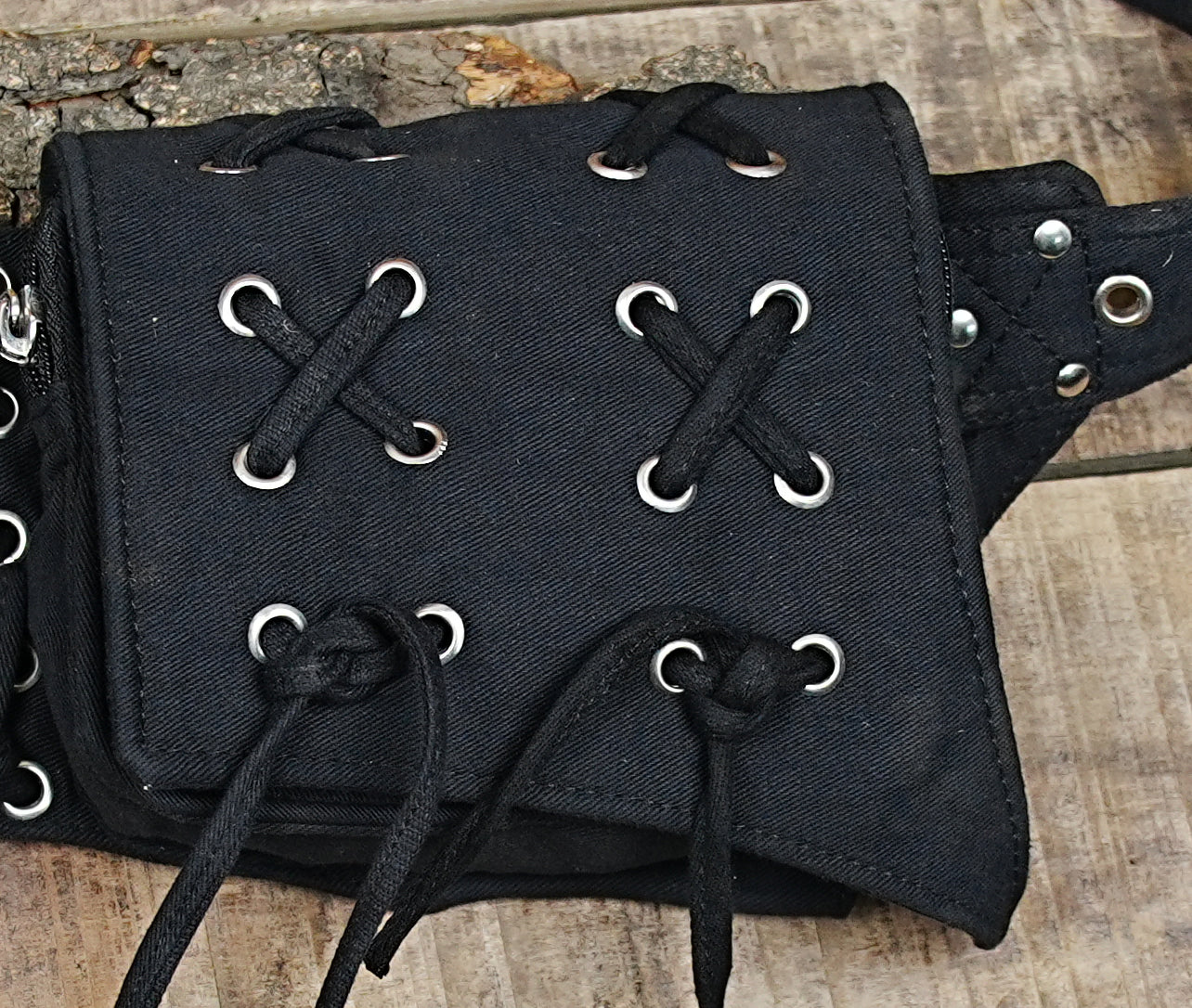 Detailed shot of a utilitarian hip pouch with a robust metal buckle and grommeted adjustment holes.