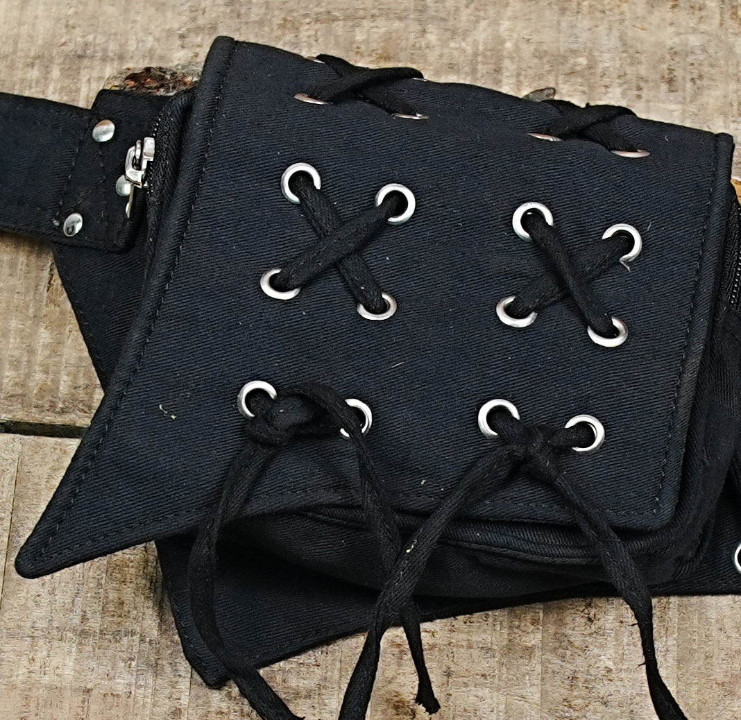 Adjustable canvas waist belt bag featuring detailed lacing, silver metal studs, and functional D-rings.