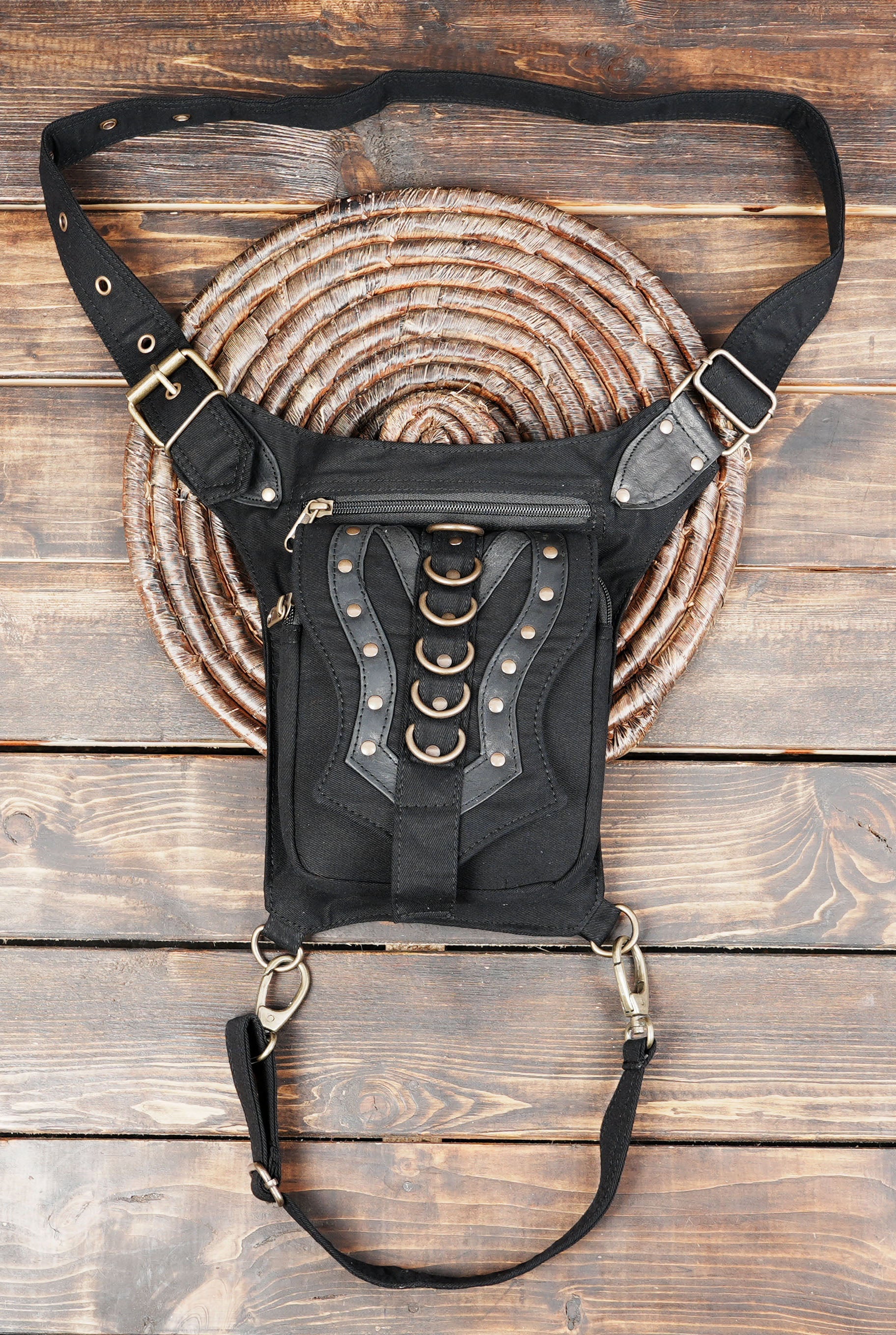 Handmade cotton canvas drop leg bag with brass metal rings and stud accents laid flat on a neutral background.