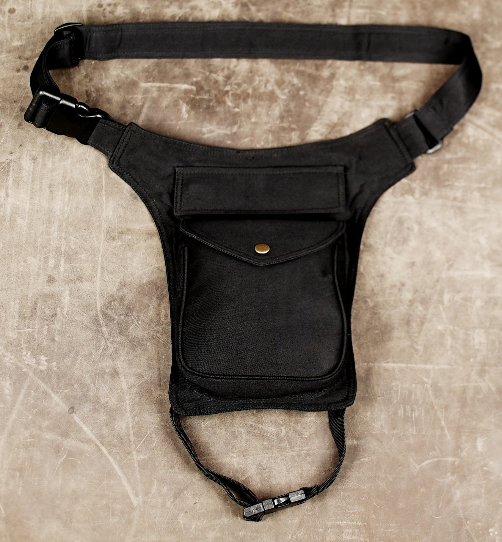 Black steampunk style thigh bag with waist strap and snap pocket.