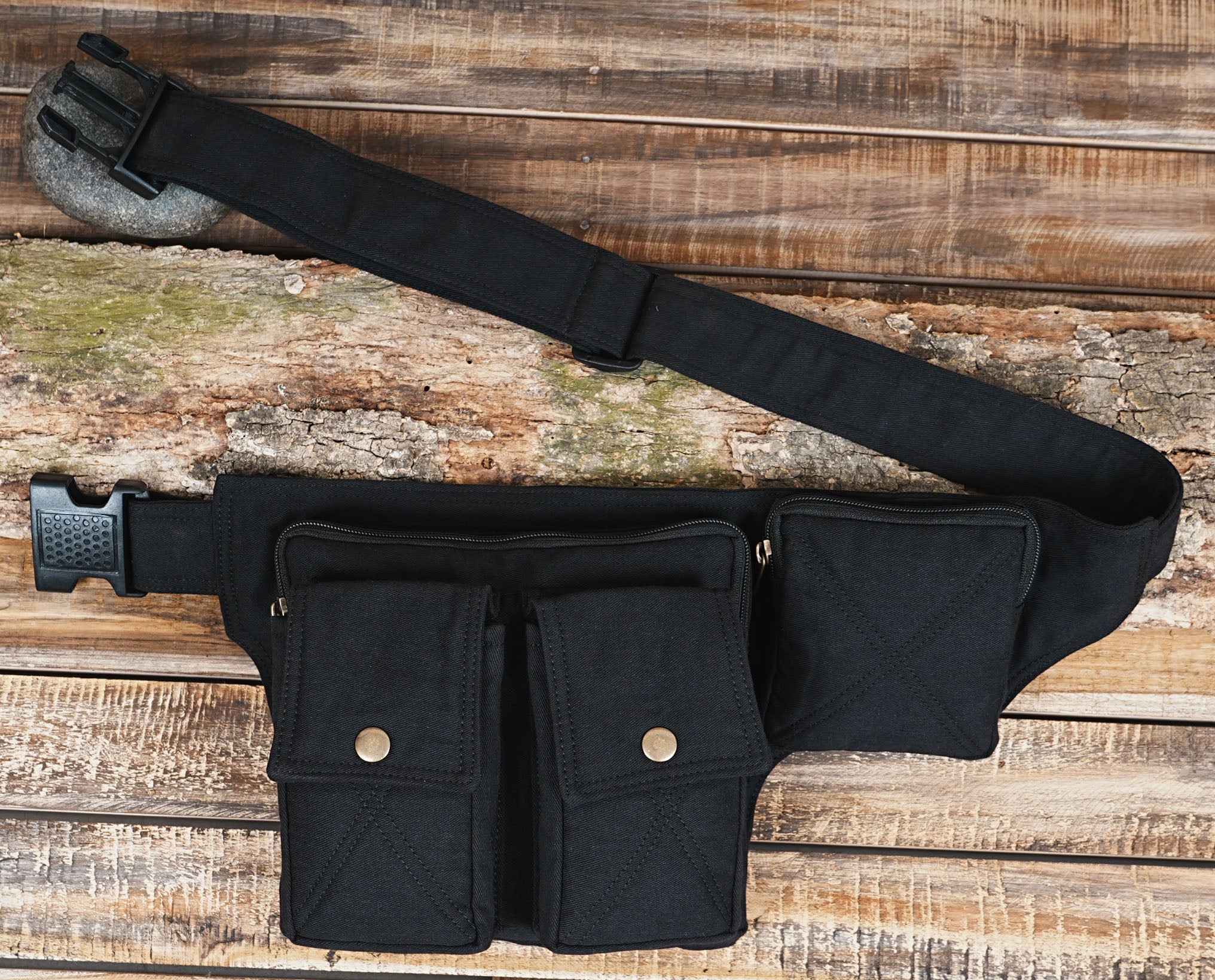 Black canvas tactical fanny pack laid flat on wooden background