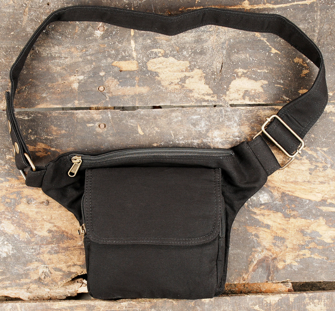Black cotton utility belt with front flap pocket on a rustic wooden background