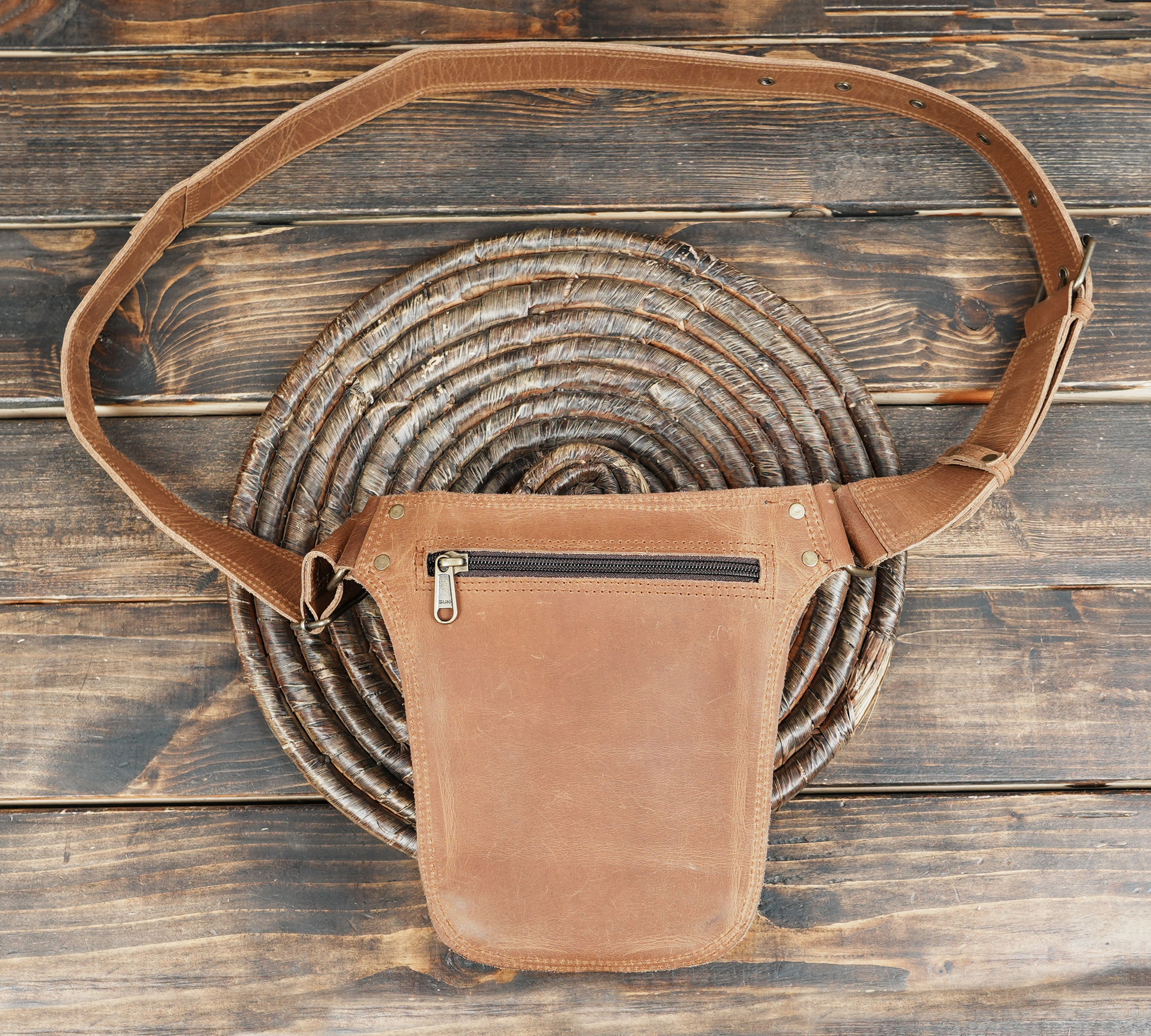 Handmade utility leather belt with decorative lacing pattern.