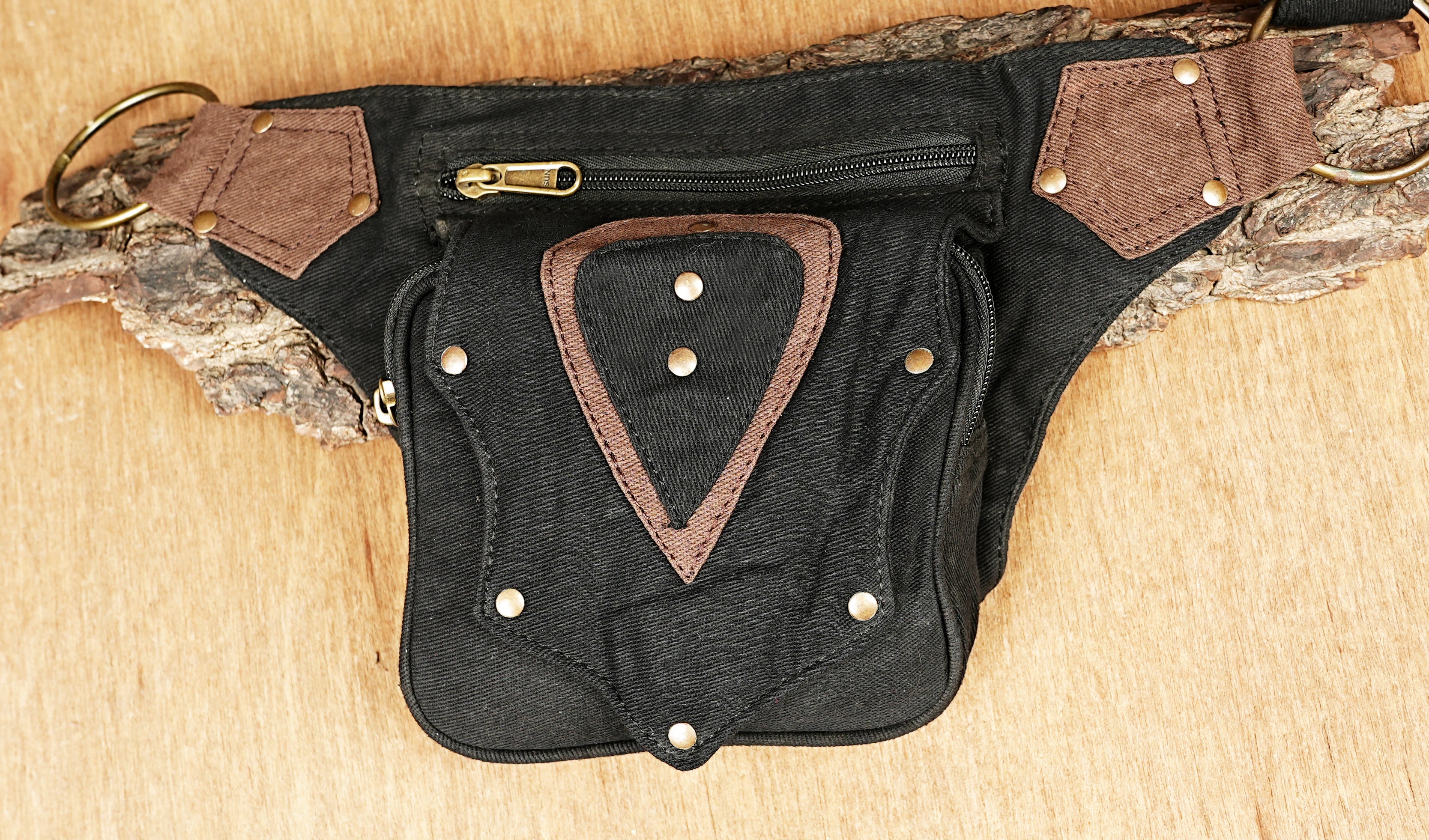 Hip bag with an adjustable waist strap and unique patchwork design on durable black canvas.