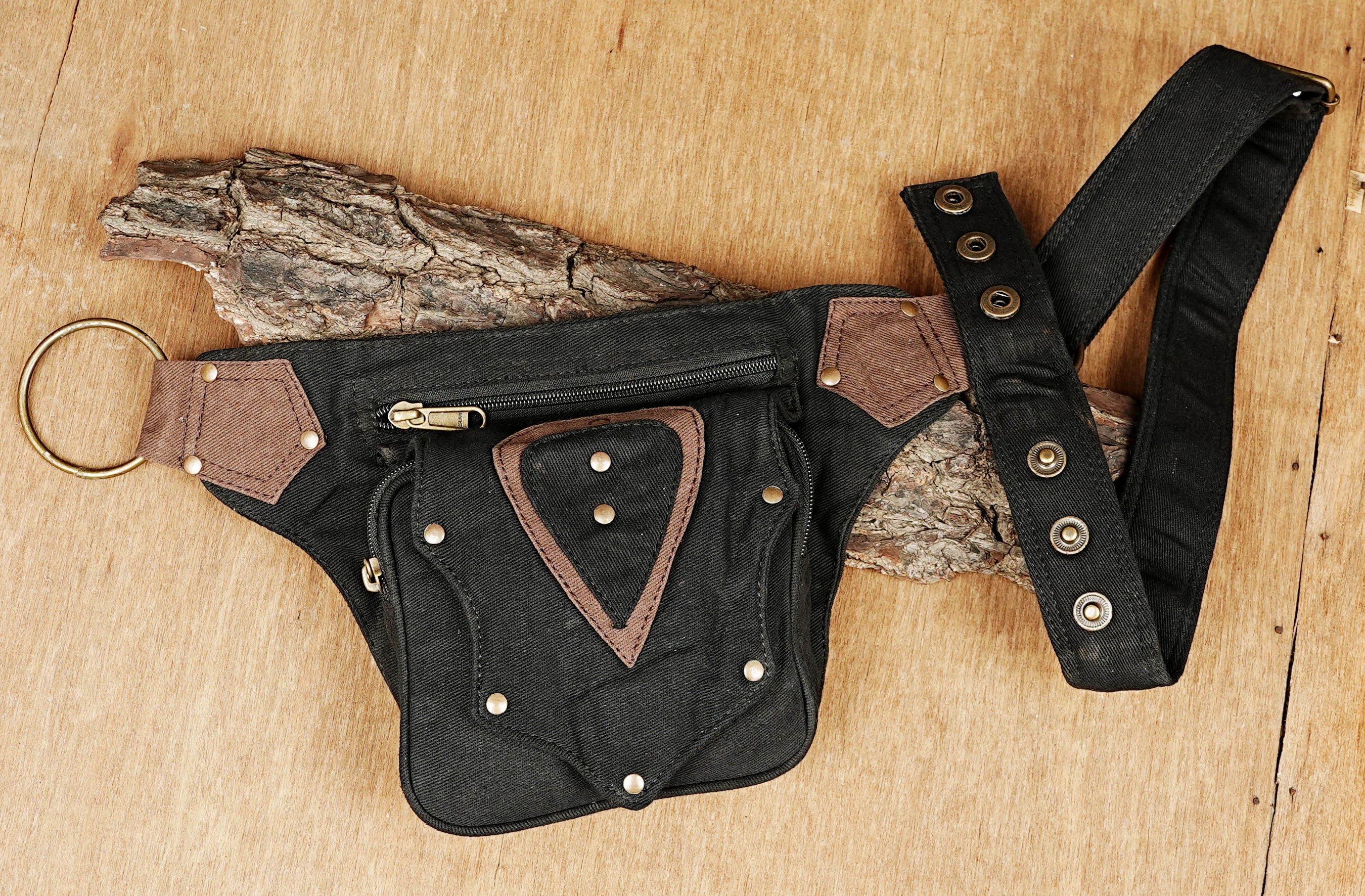 Small canvas shoulder or fanny pack with industrial-style brass rings and rivets.