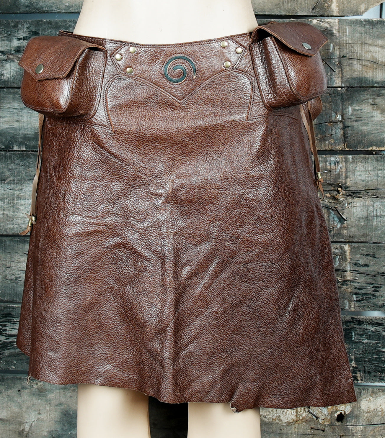 Brown leather utility skirt with multi-pocket design, ideal for cosplay and steampunk fashion.