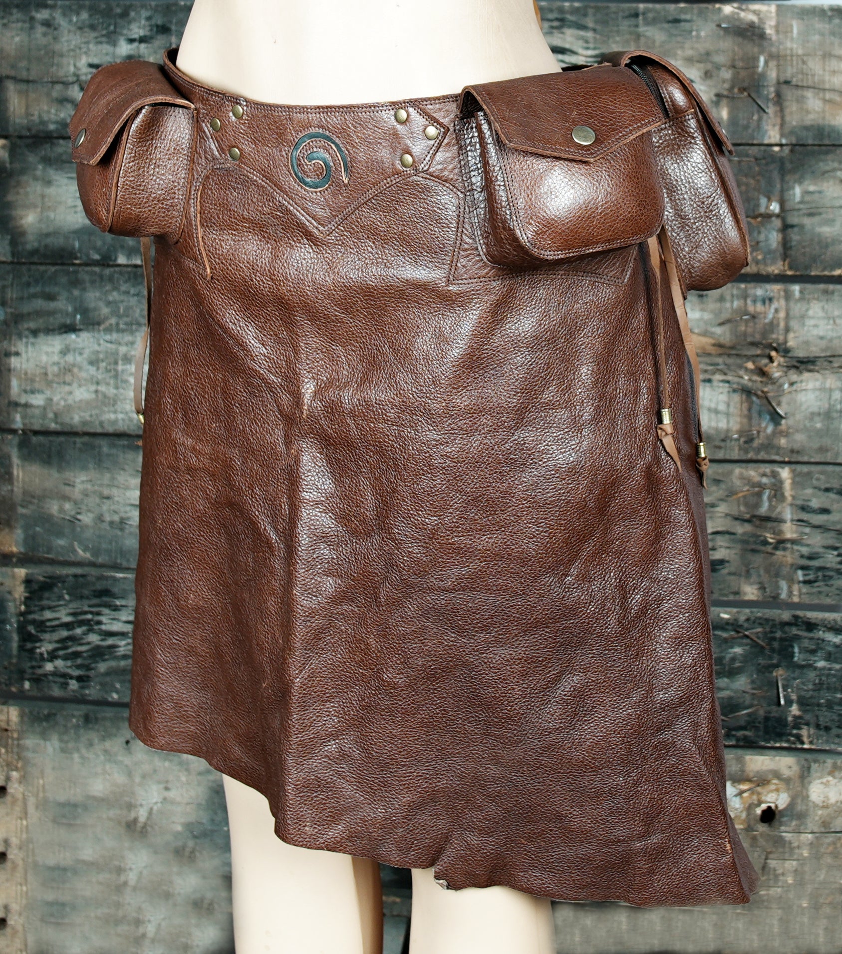Festival-ready leather skirt with rustic brown finish and functional utility pockets.
