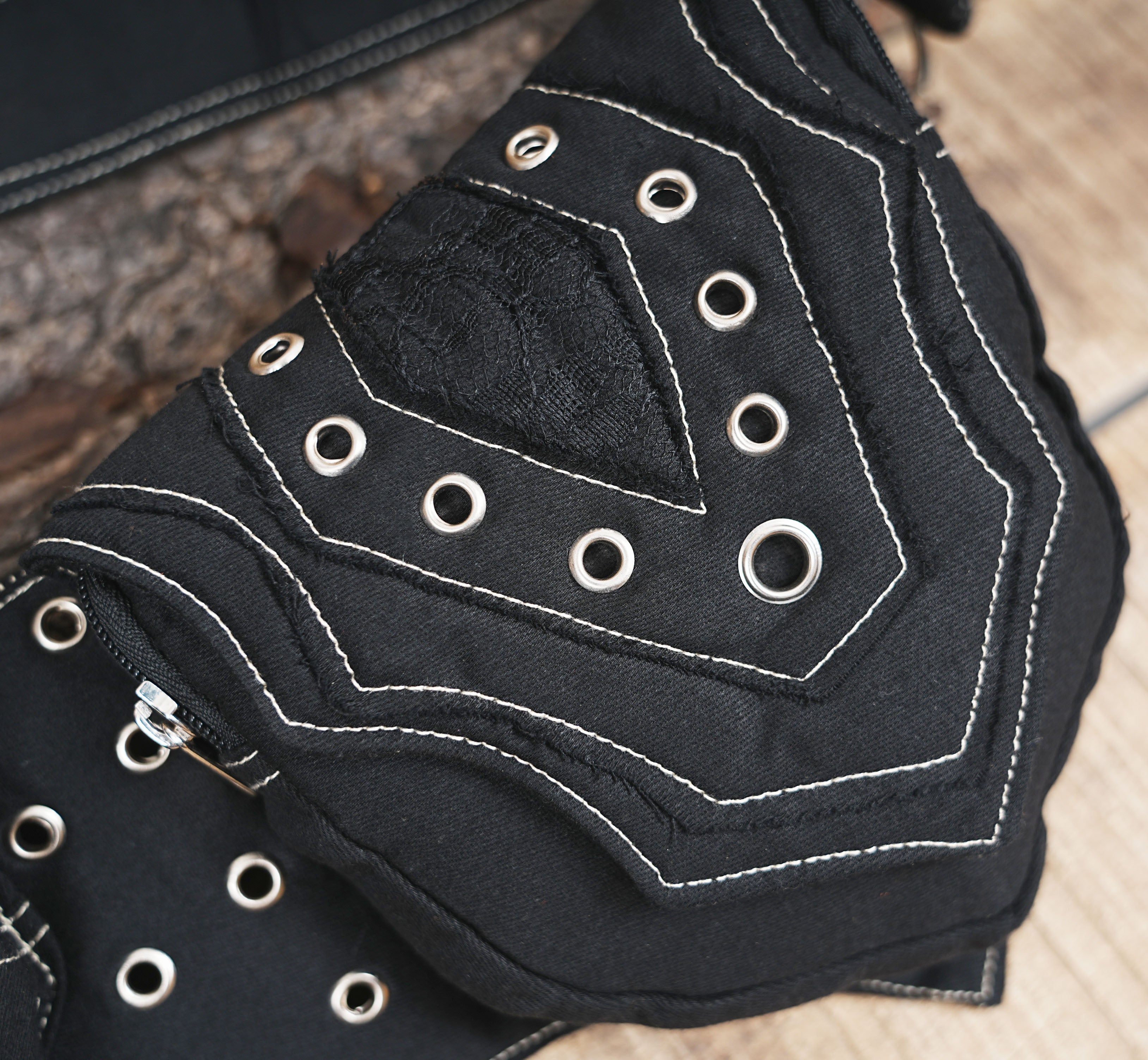 Utility hip pouch made of durable black canvas with metal eyelets and contrast stitching.