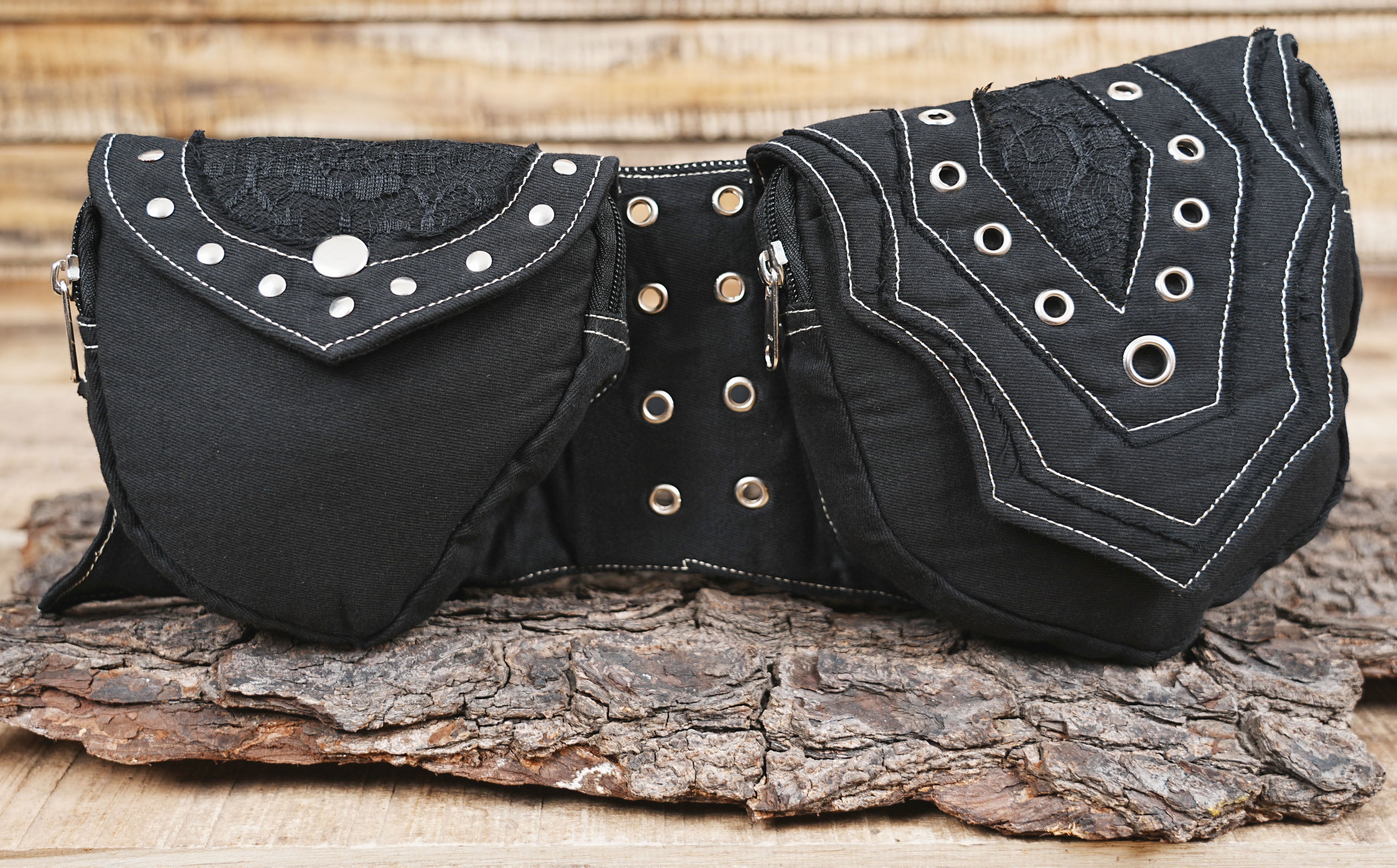 Functional black utility waist bag with adjustable belt, shown against a piece of natural wood.