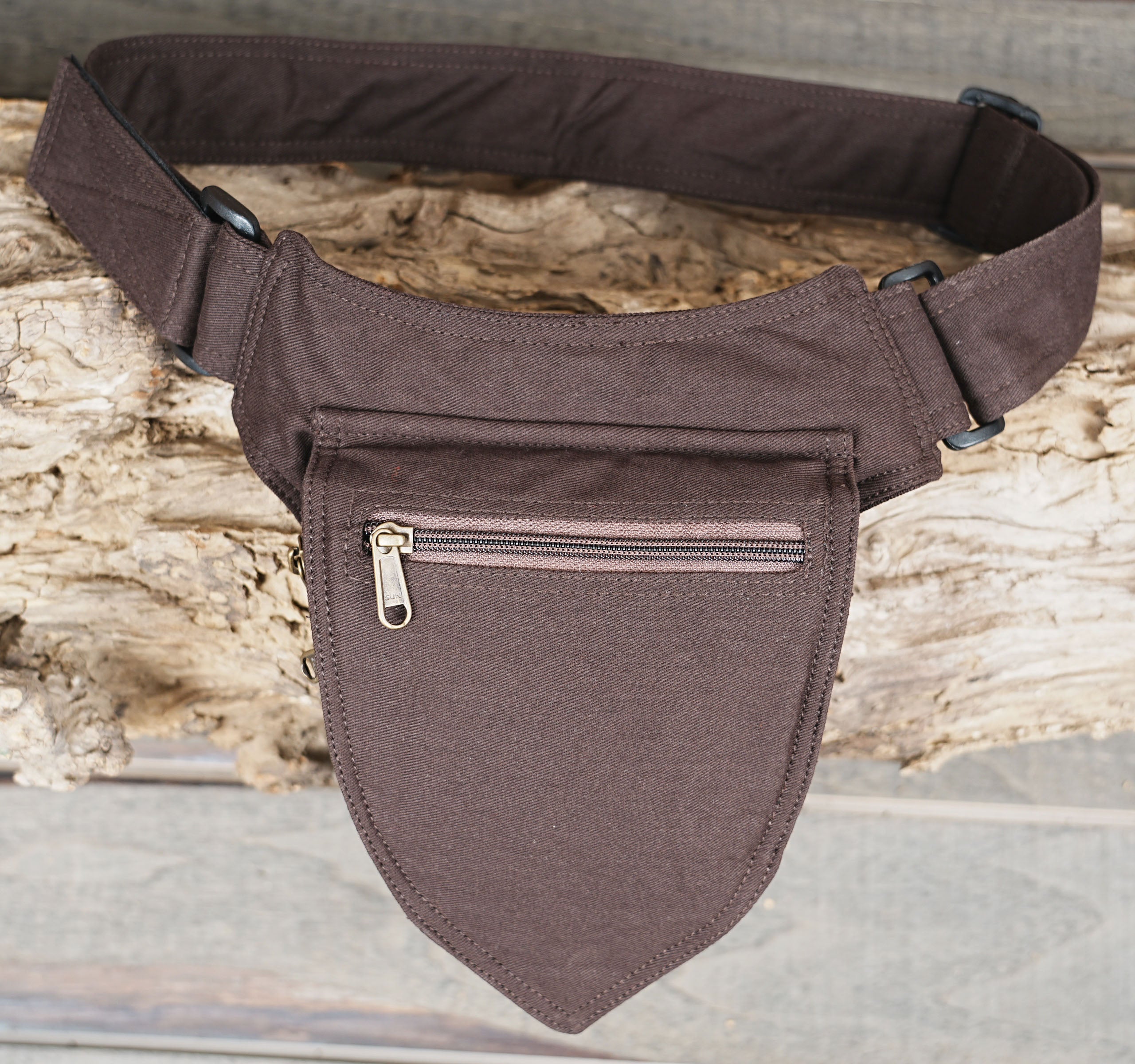 Adjustable black hip bag shown against natural wood backdrop