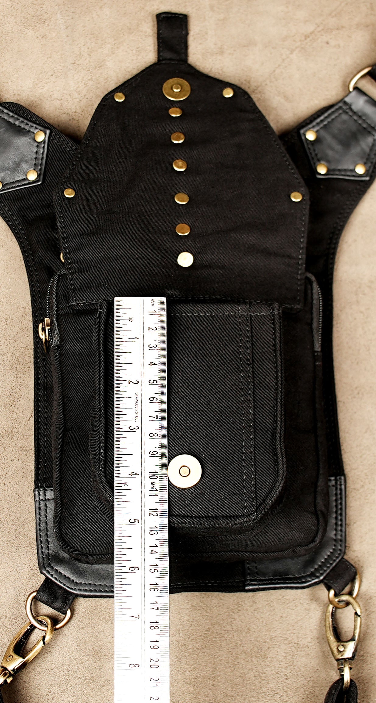 Multi-pocket cotton thigh bag with studded metal hardware on neutral backdrop.