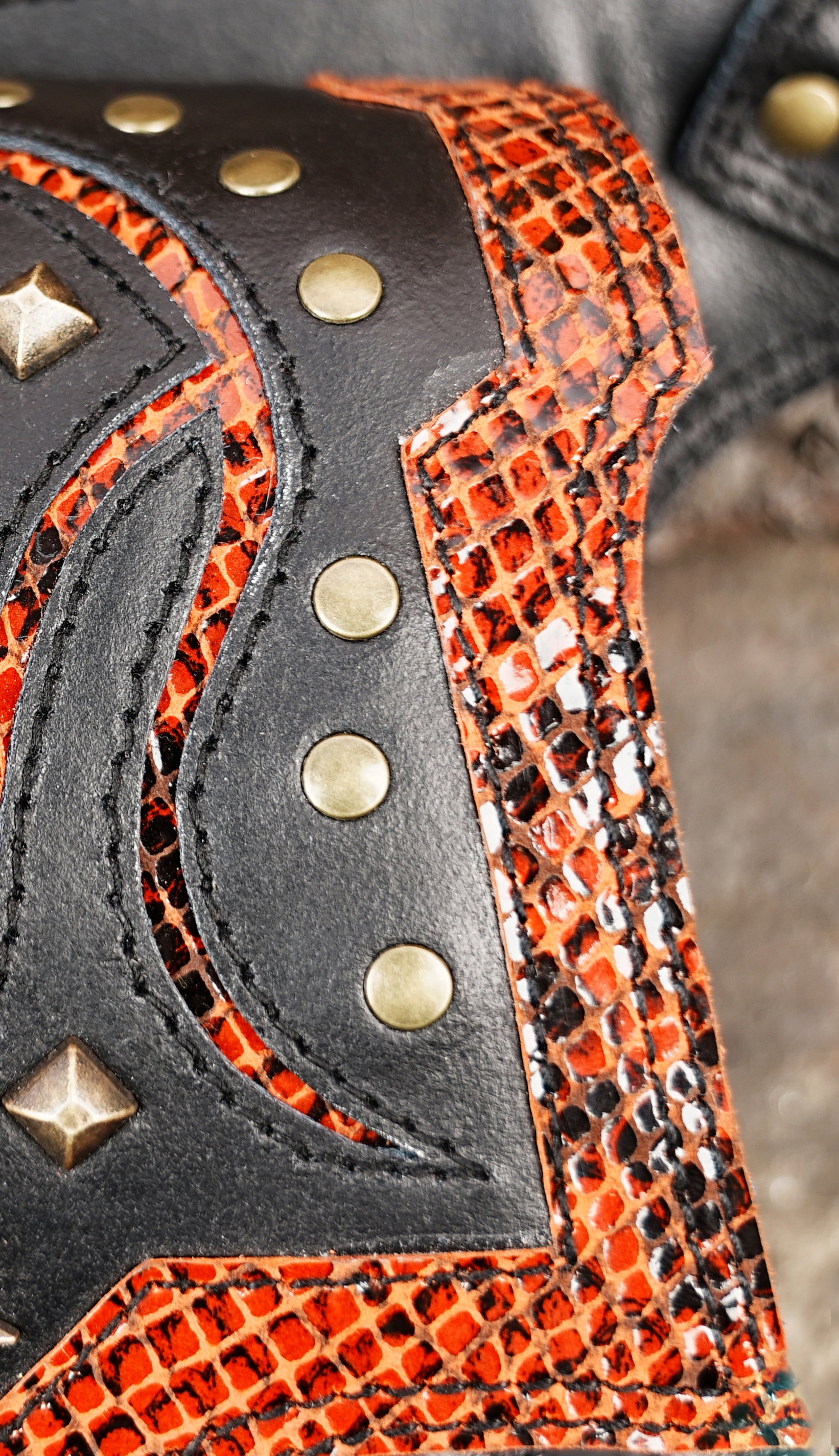 Leather waist belt with bold red accents, studded scrollwork, and fringe