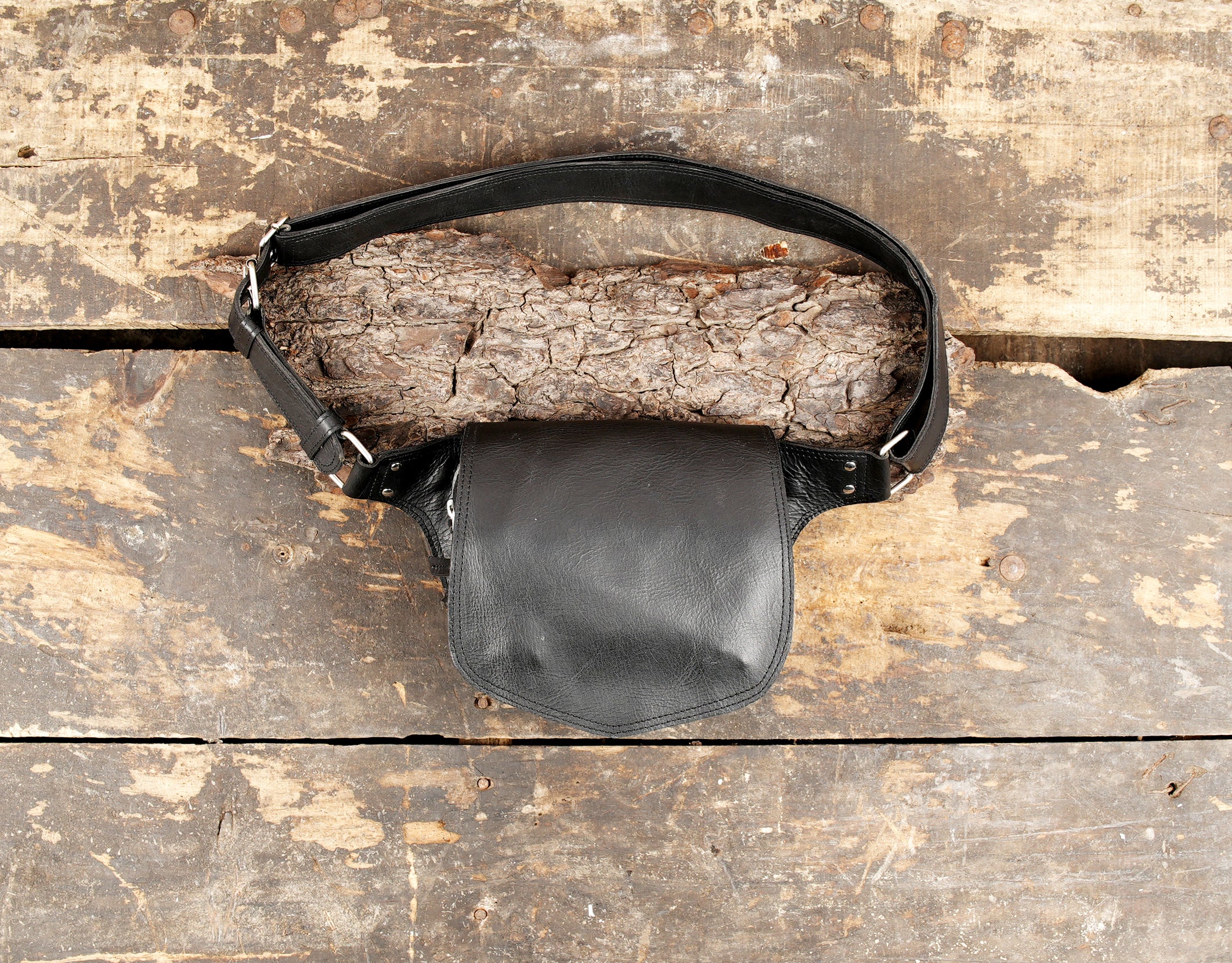 Black leather waist belt pouch with adjustable strap on wooden background
