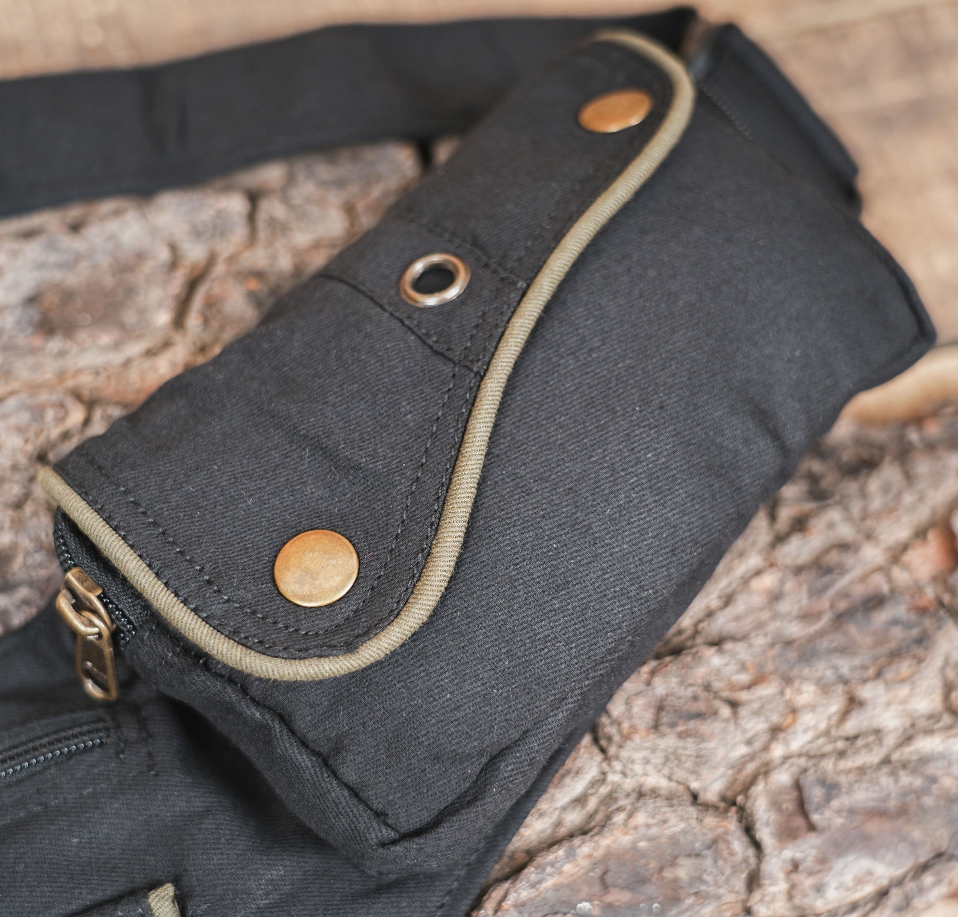 A black canvas hip bag designed for travel and festivals, showing the side release buckle and adjustable strap length.