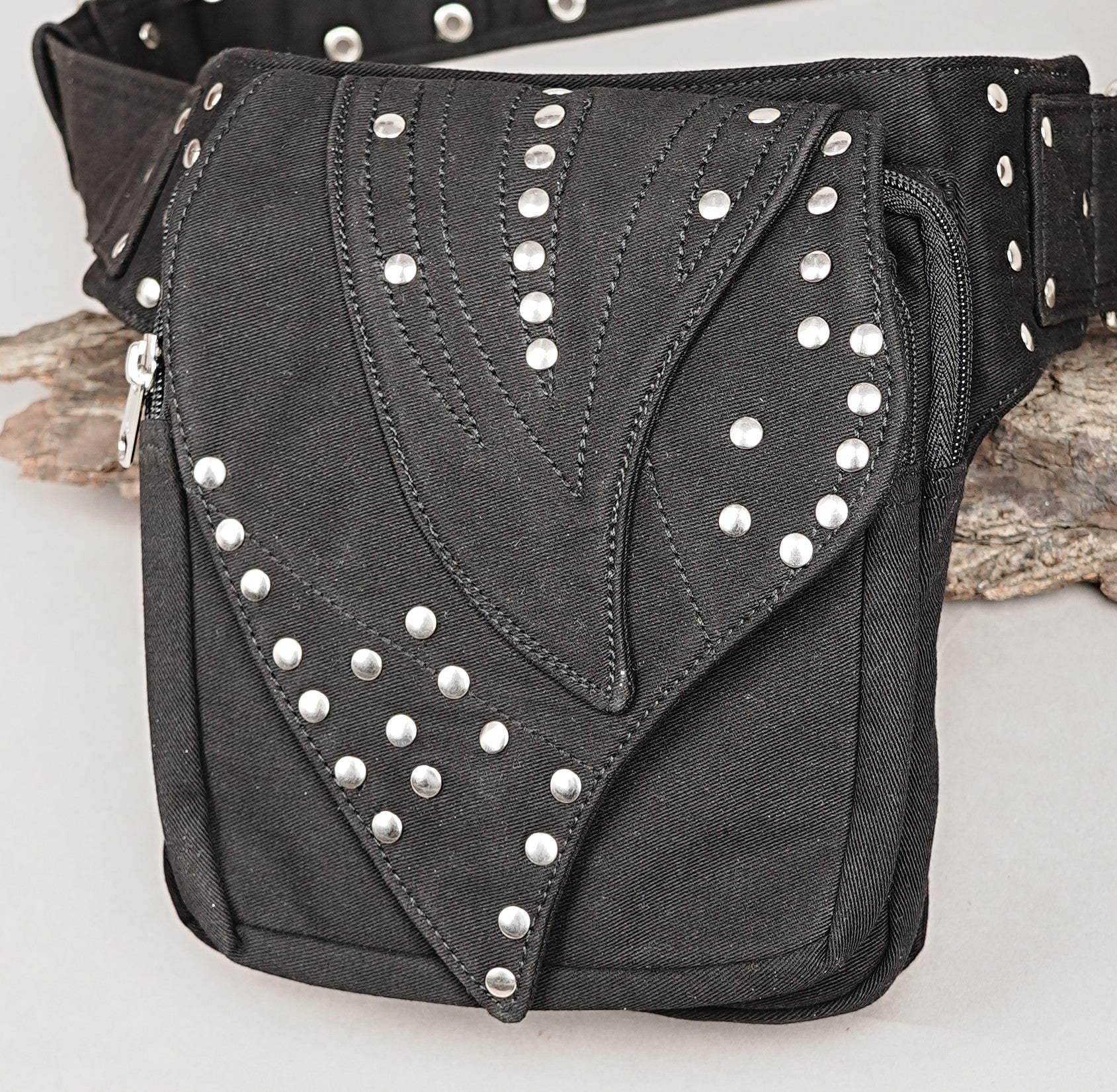 Multi-compartment hip pack in black heavy-duty canvas, shown against a rustic wood background.