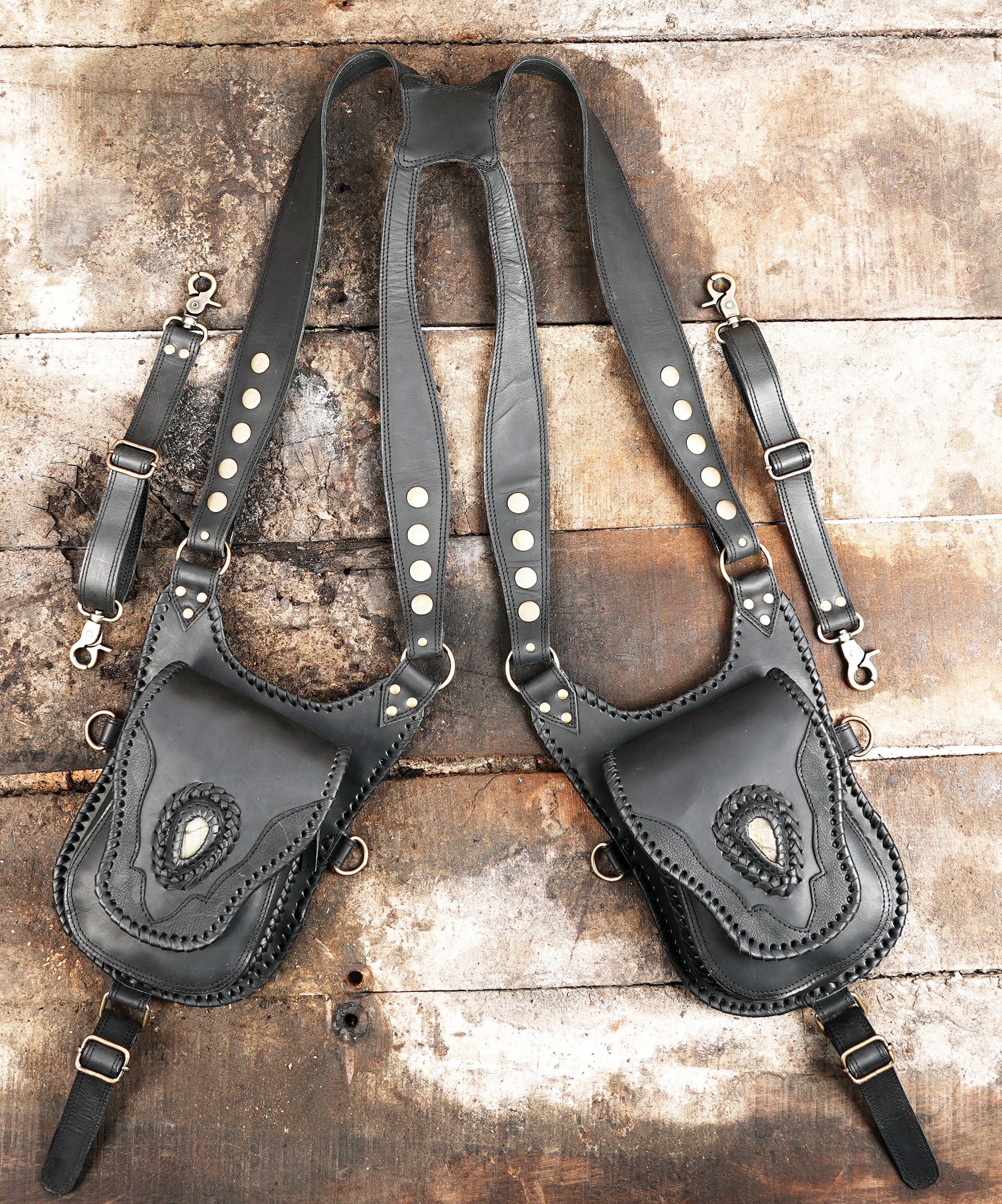 "Black leather holster harness with dual carved pouches"