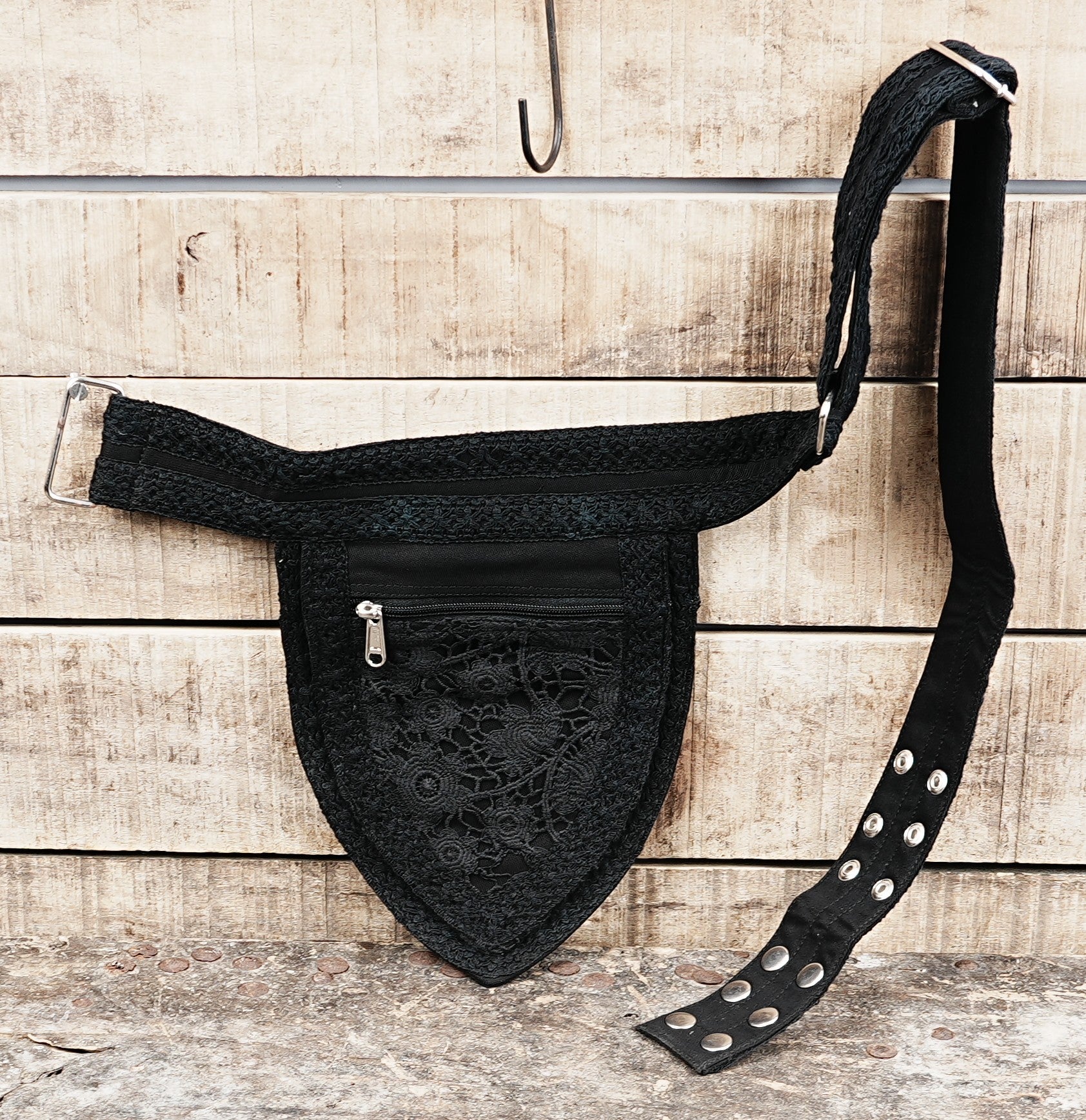 Product view of a black studded waist bag featuring soft lace texture and two metal rings.