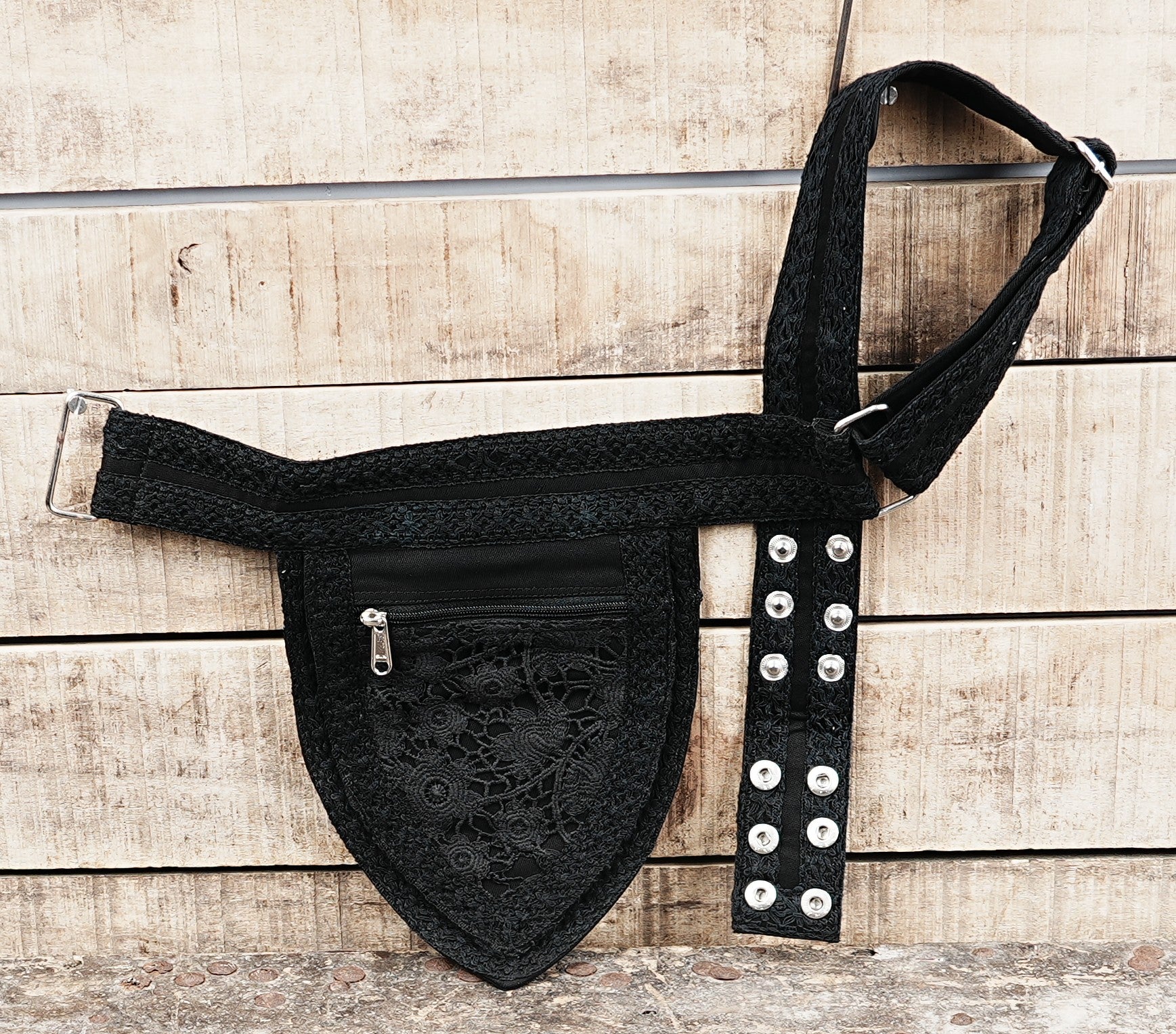Adjustable black cotton canvas bumbag with a subtle lace detail, shown on a rustic wood background.