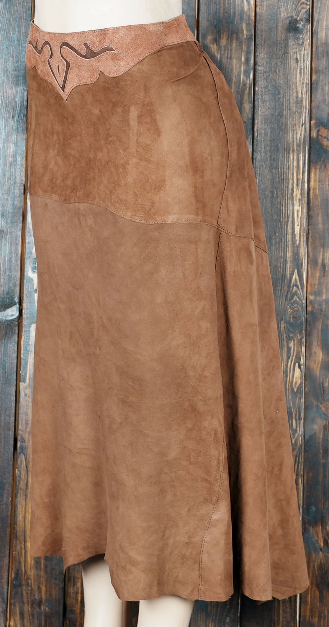 Handmade brown suede leather skirt with rustic western design on wooden background