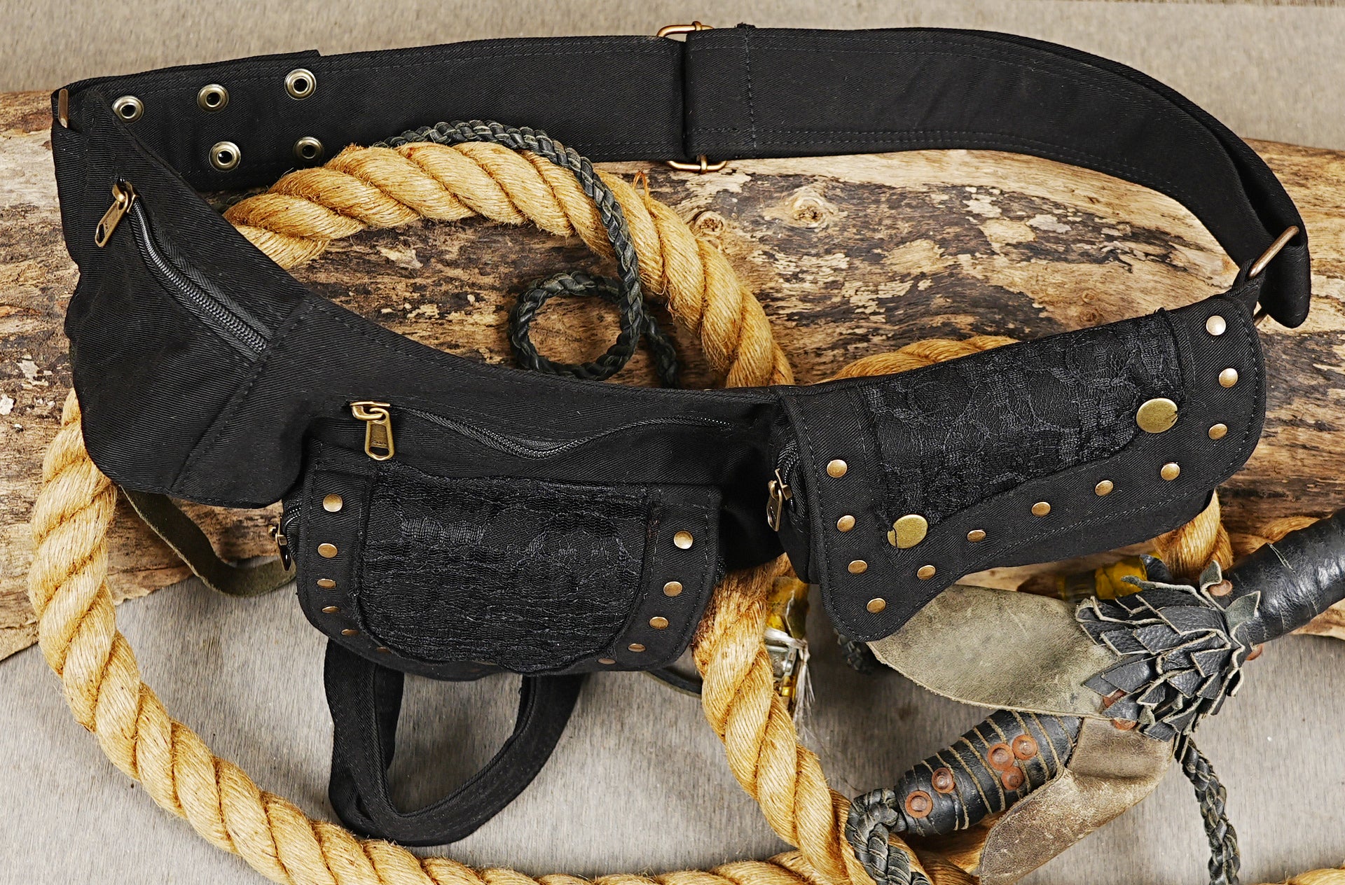Multi-pocket cotton thigh bag with brass studs and dual compartments on rustic backdrop.