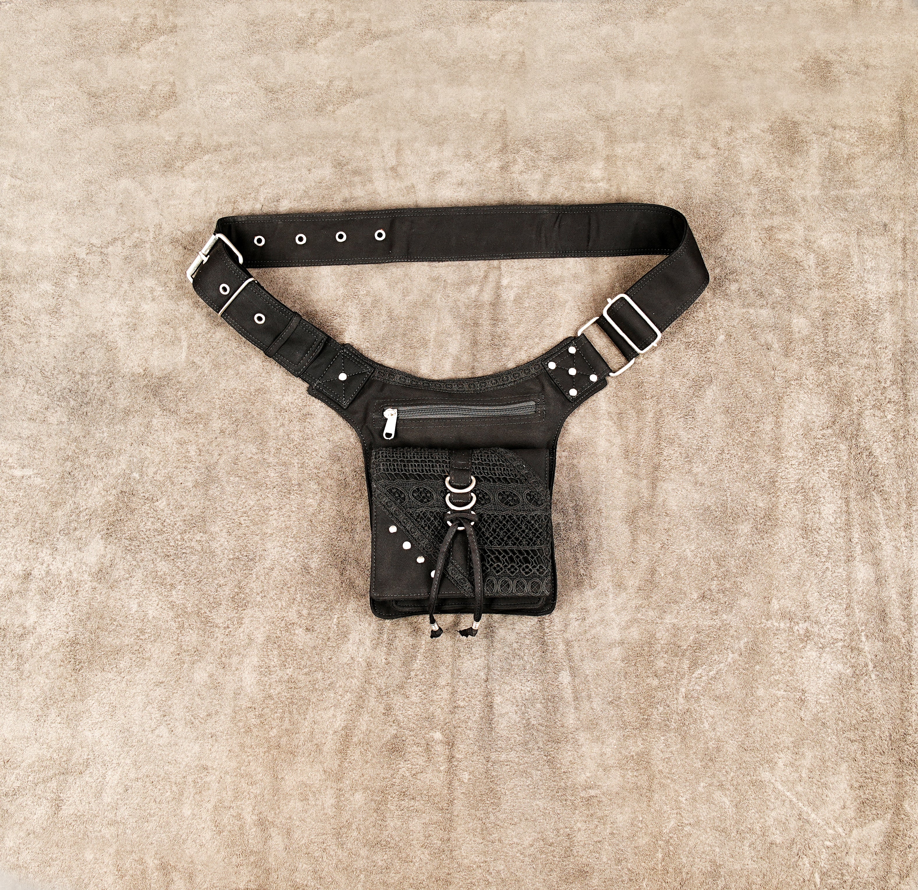 A close-up view of a black cotton utility fanny pack with a central mesh pocket and metal rings