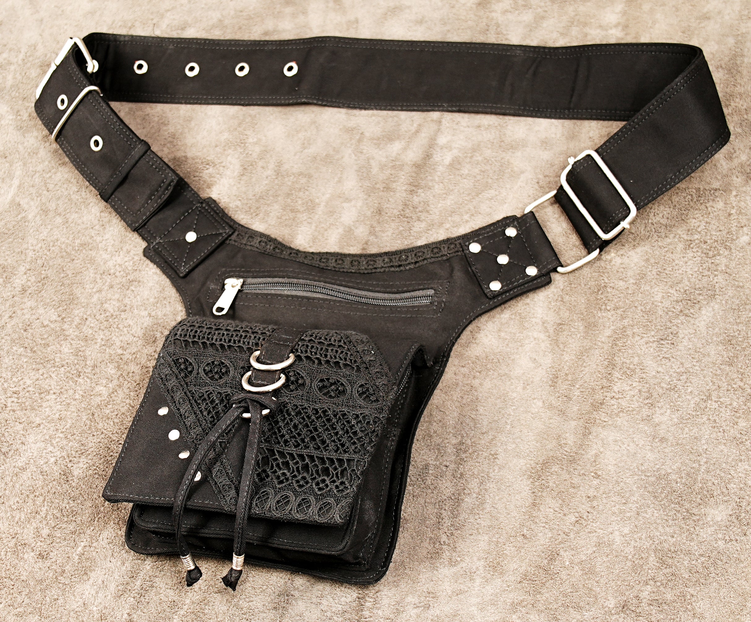 Black canvas waist belt bag with multiple zippered pockets, an adjustable studded strap, and metal buckles.