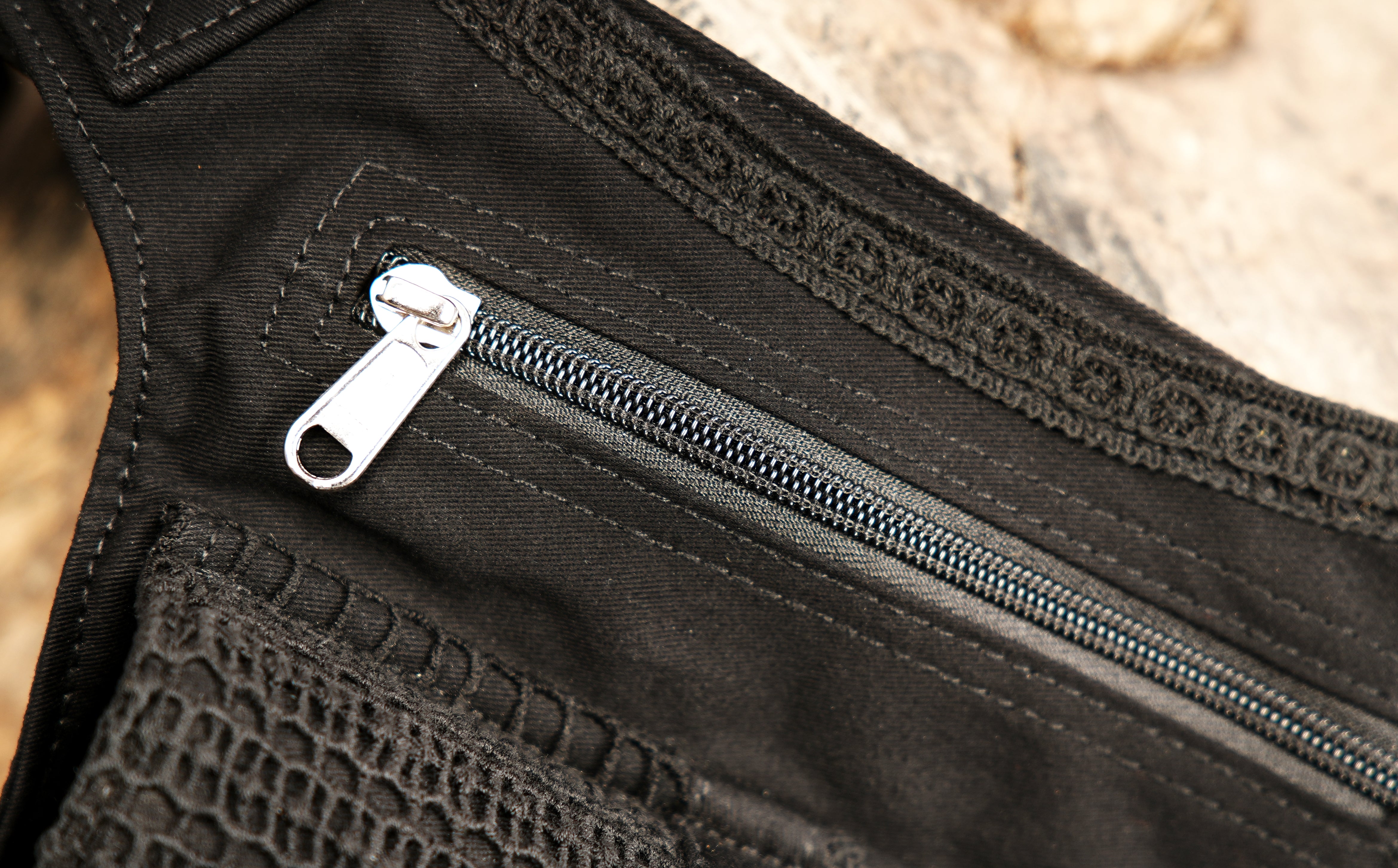 Small black money belt pouch with a central laced pocket, two metal eyelets, and durable zippers.