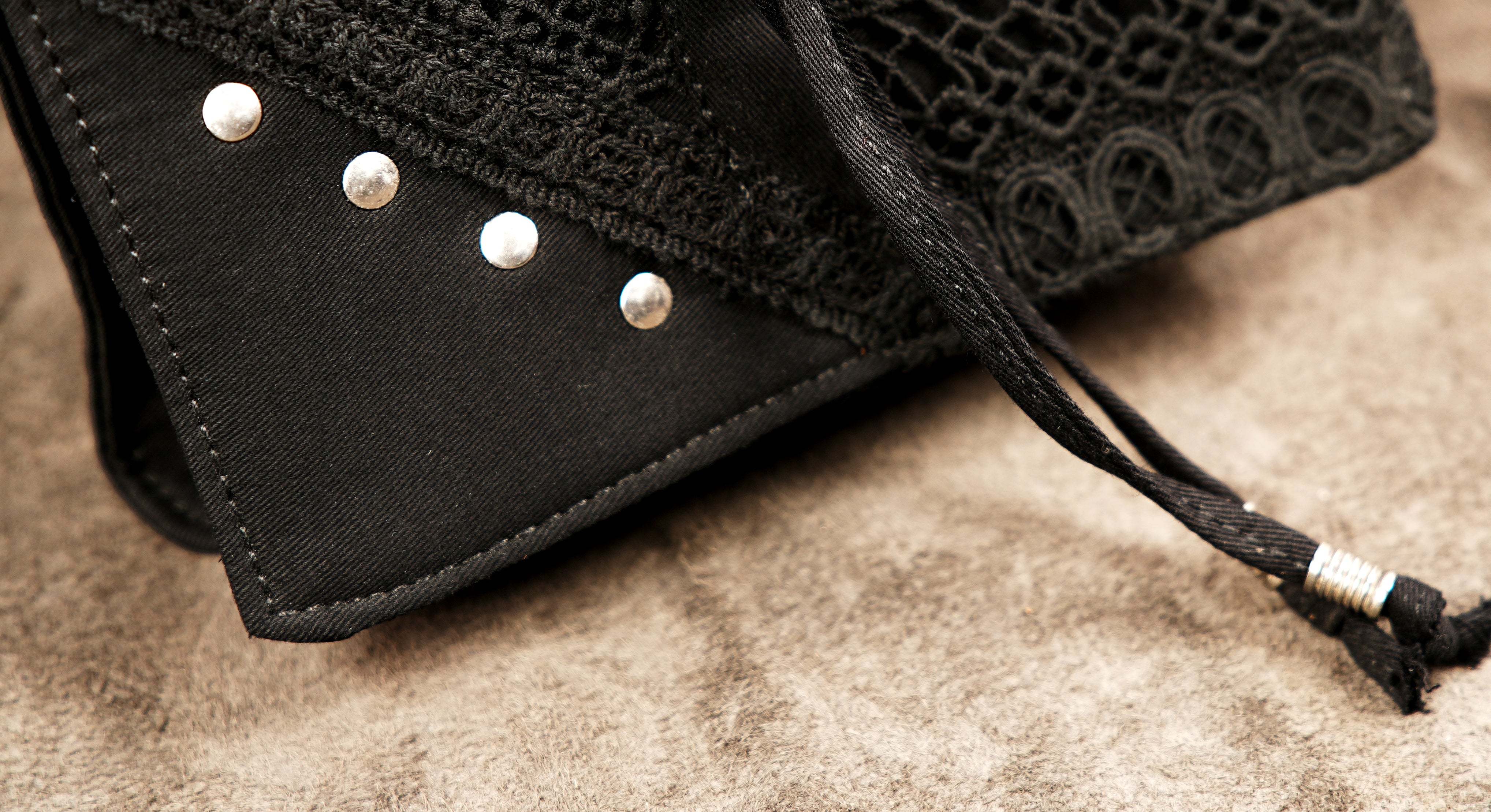 Steampunk-style black canvas hip belt bag featuring decorative eyelets, rivets, and a wide studded strap.