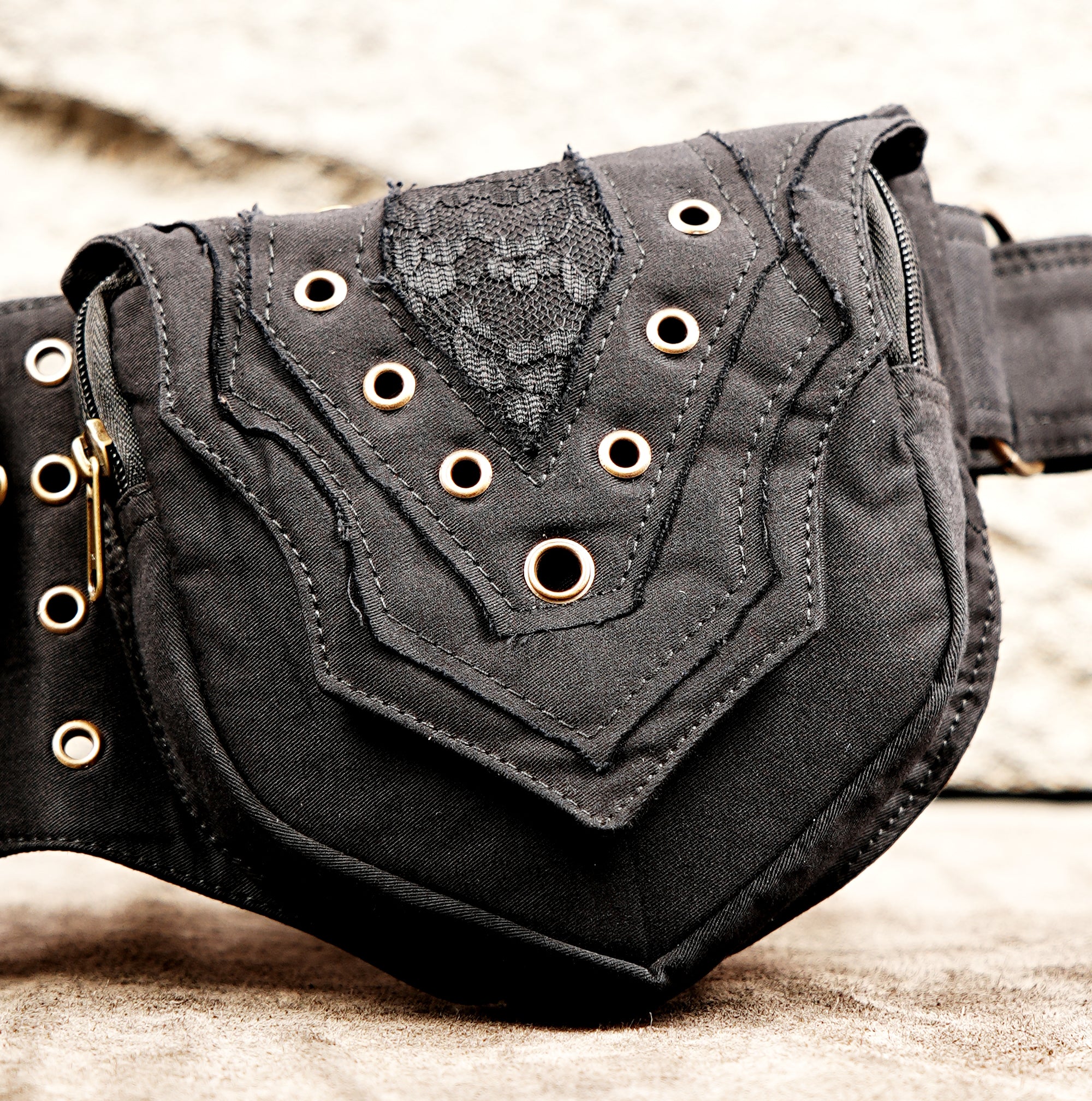 Black canvas hip bag with grommet trim and gold hardware accents