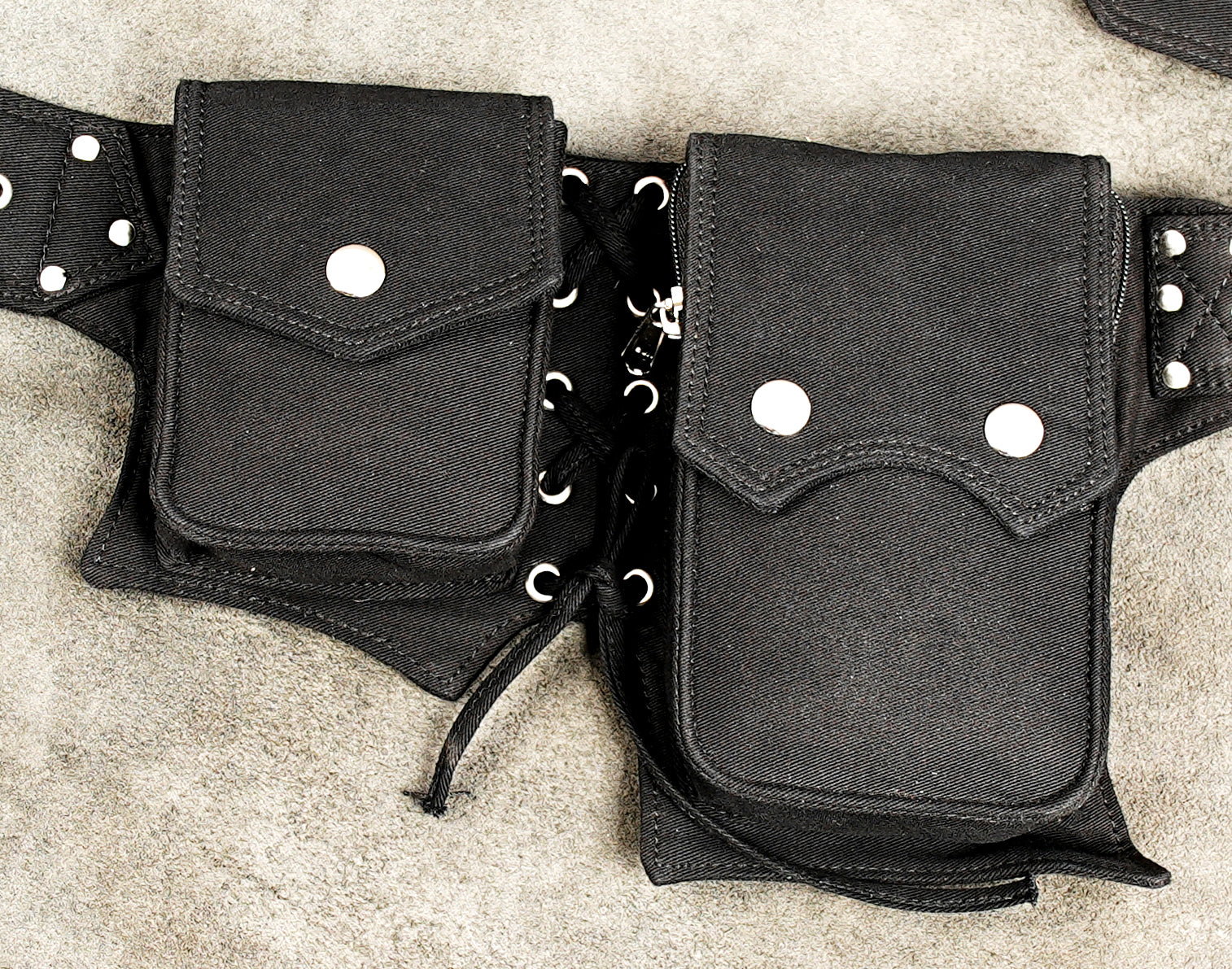 Adjustable waist pack with two large pockets and decorative grommet belt strap.