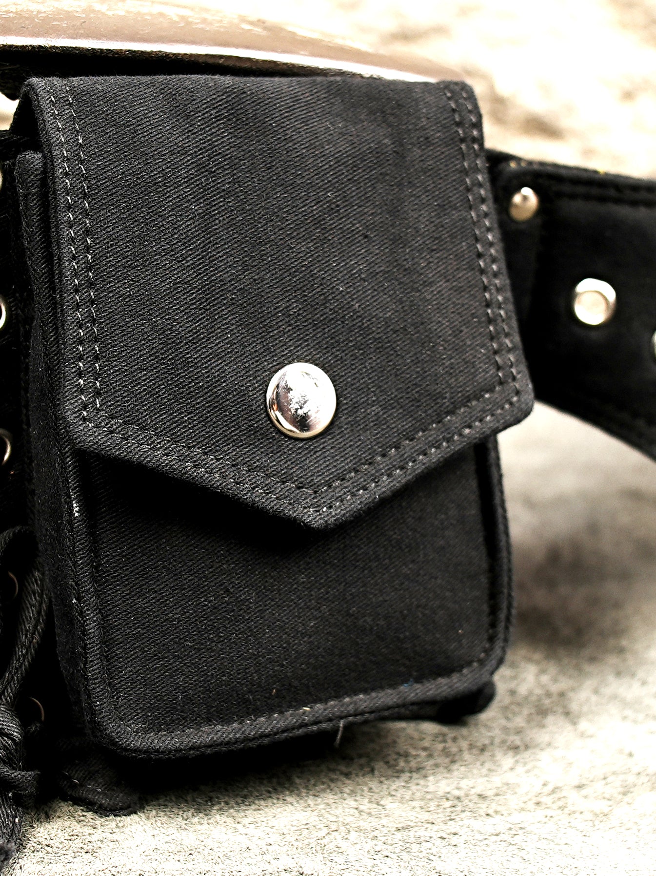 Unisex black hip belt bag featuring secure snap-button pockets and silver buckle.