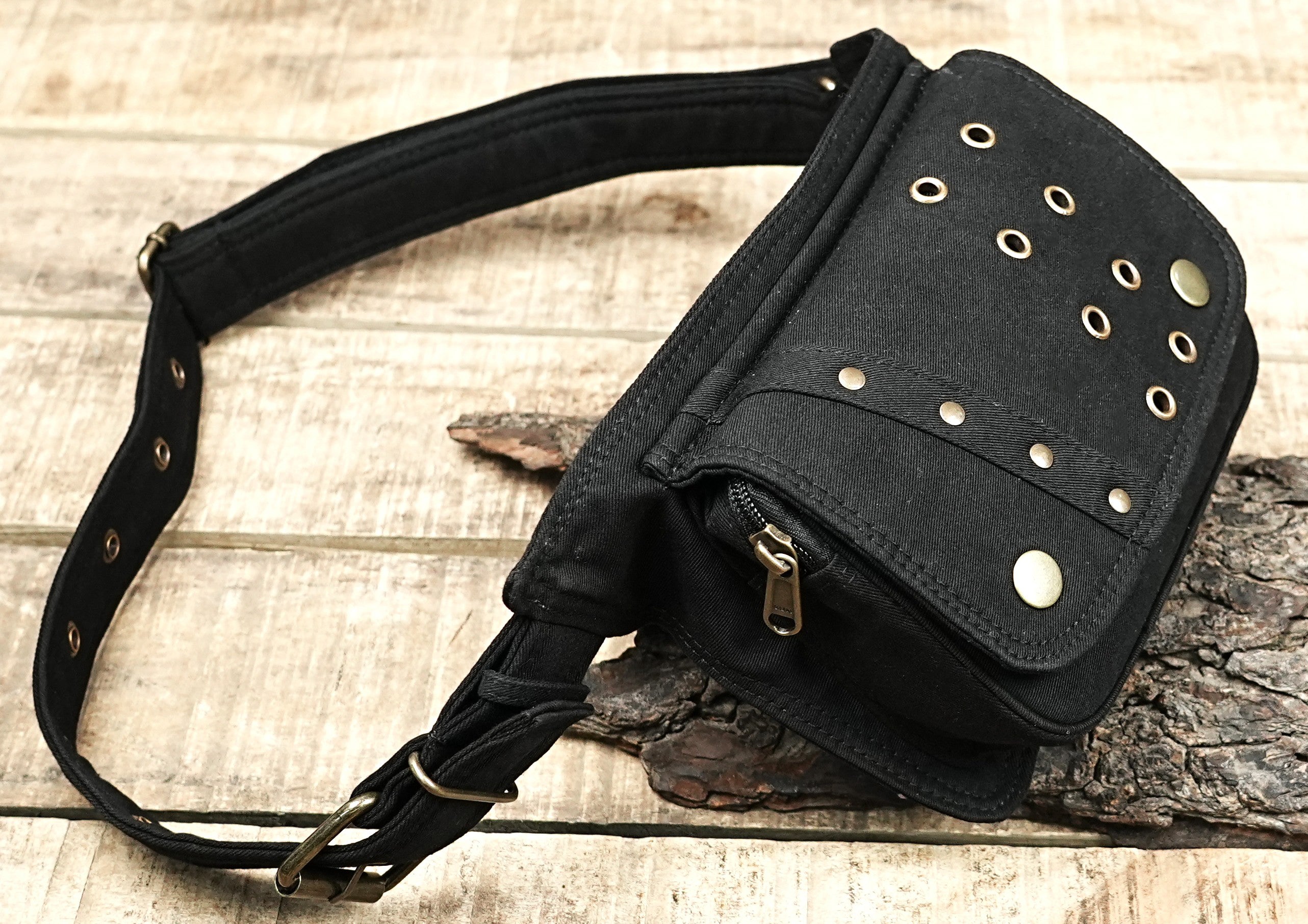 Durable black canvas fanny pack with a fold-over flap pocket and eyelets.