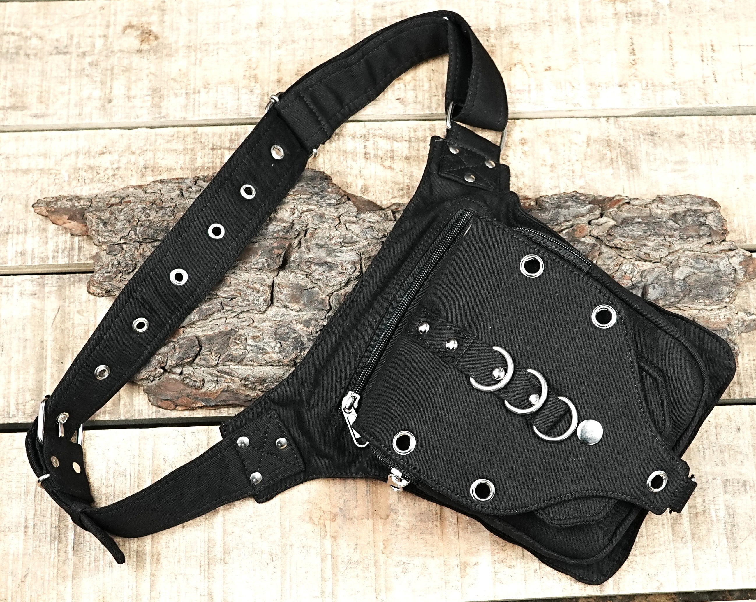"Durable black canvas drop leg bag with a tactical, grunge aesthetic, providing hands-free storage with several pockets and silver hardware." (Australia/USA)