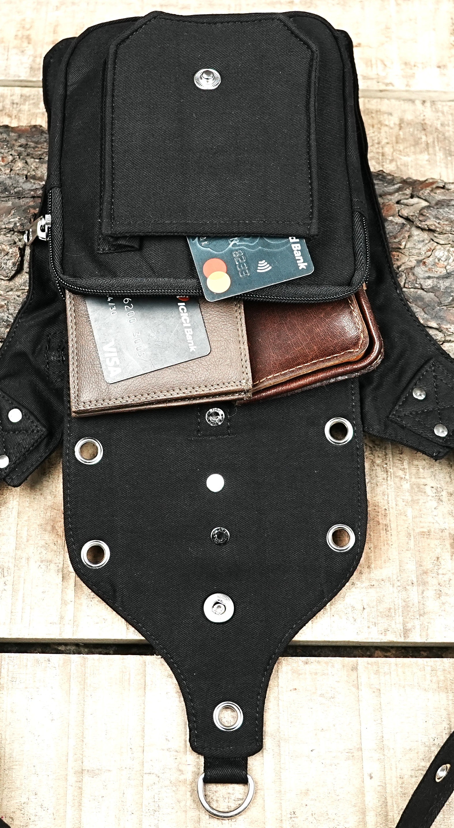 "An adjustable black canvas waist belt bag with a tactical vibe, featuring multiple zippered pockets, metal grommets, and three O-ring details." (General)
