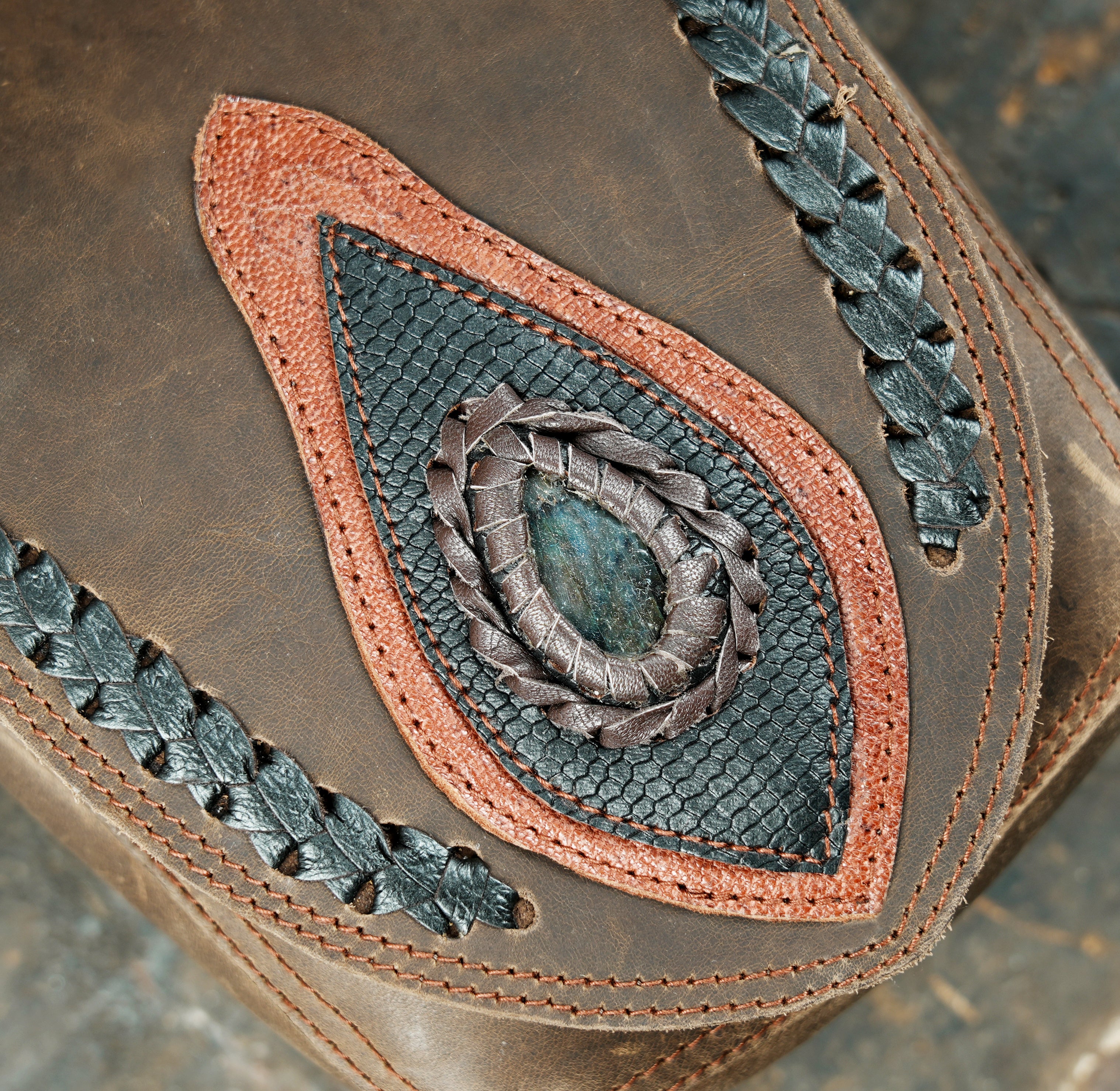 “Rustic brown leather holster with braided edges and teardrop stone detailing”