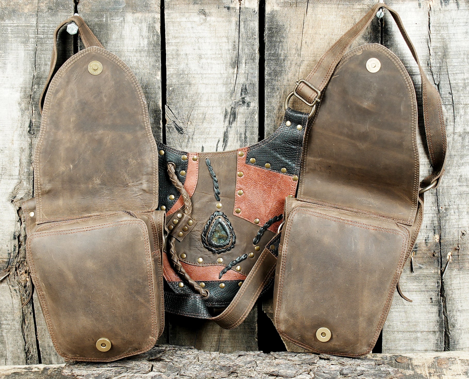 “Brown leather shoulder rig with patchwork flap and stone detailing”