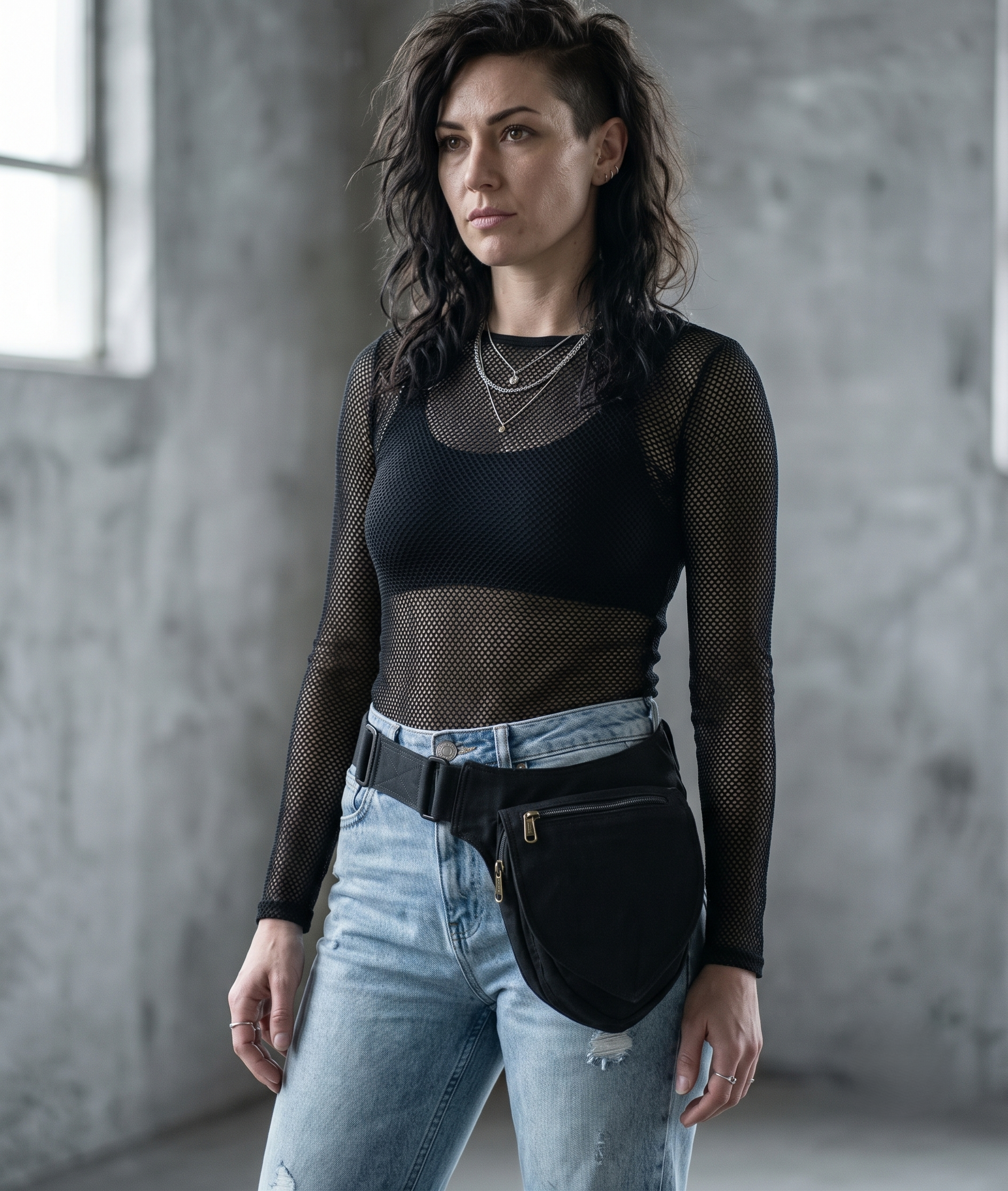 Black cotton canvas hip bag with brass zipper and adjustable strap on a wooden background