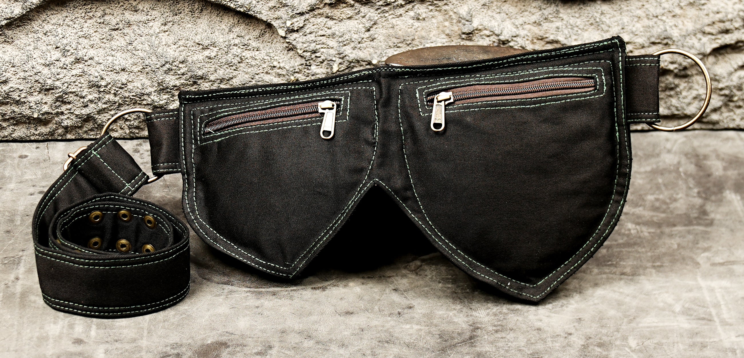 Adjustable black canvas belt bag with two leaf-shaped pockets and brass slide buckle