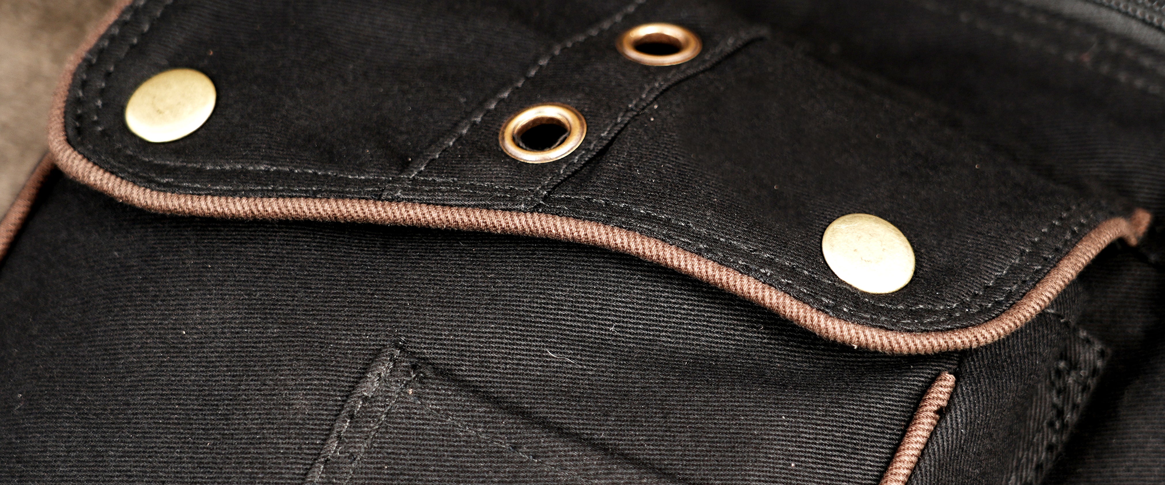 Black canvas hip pack with flap pocket and eyelet details