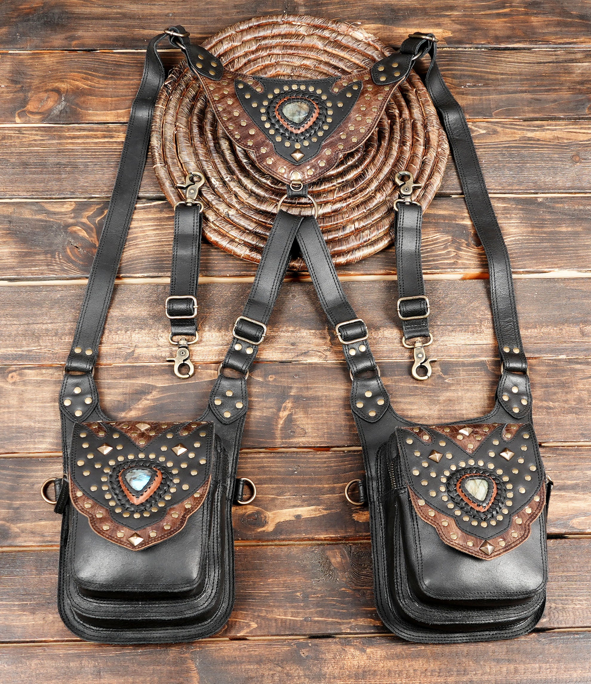“Black leather double holster with gemstone accents and brass studs on rustic wood background”