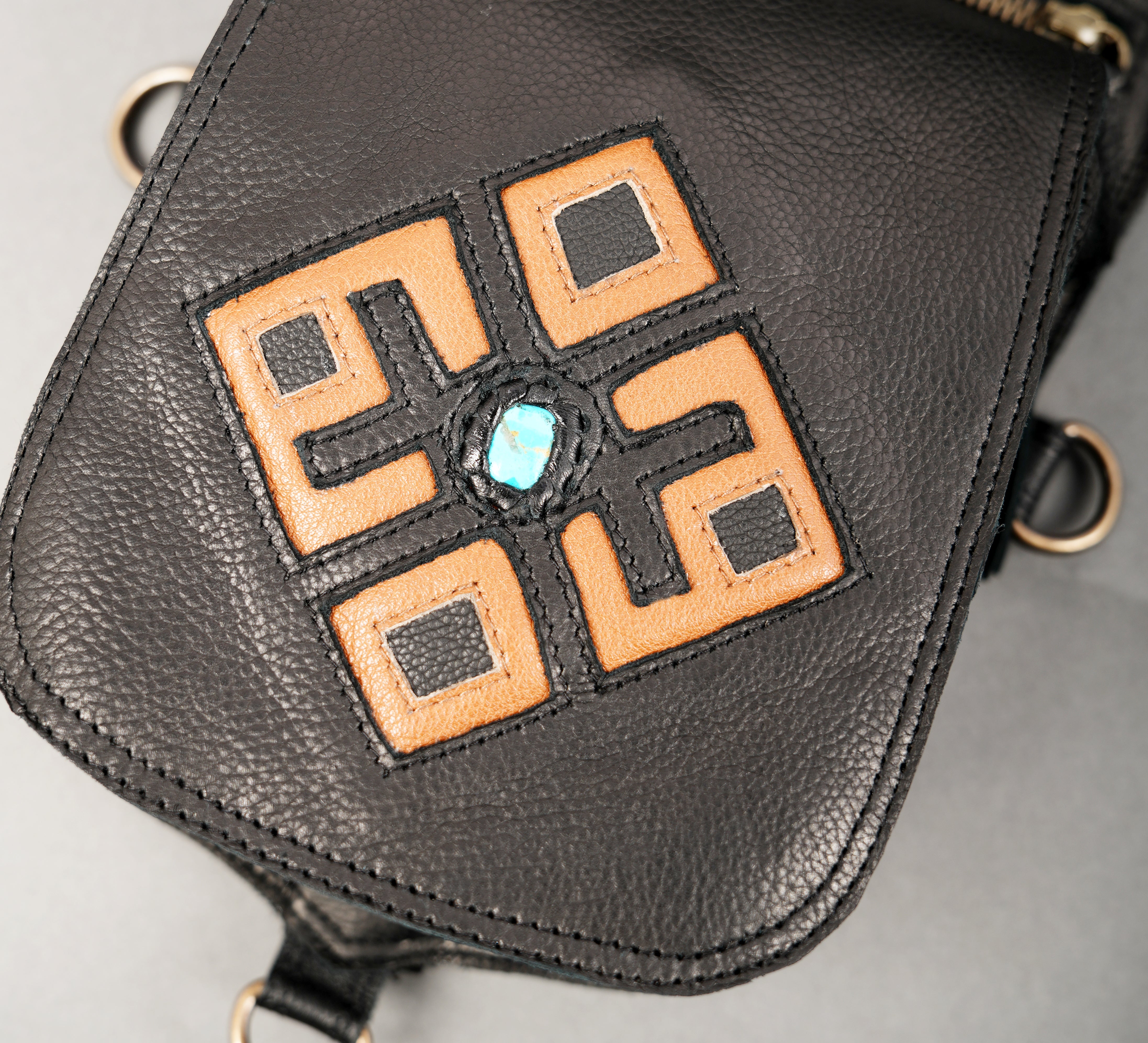 Black leather bag with ornamental blue stone accents.
