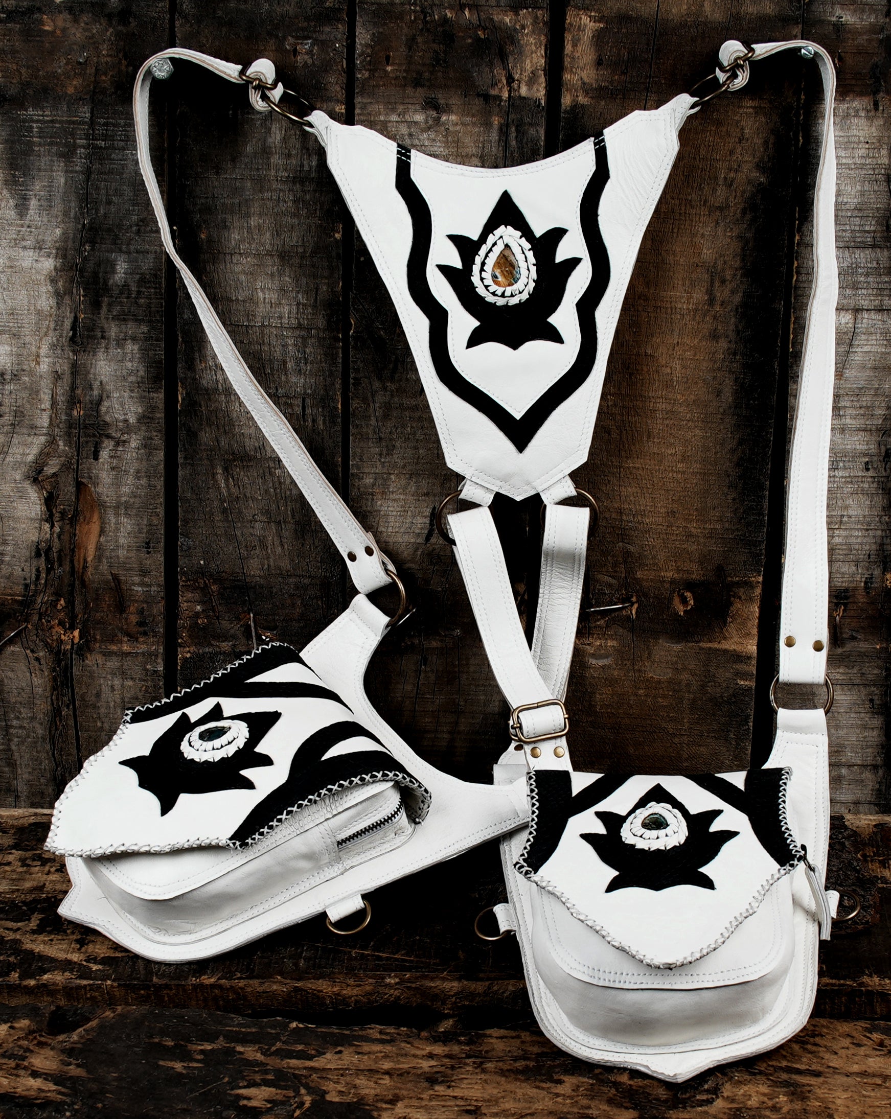 “Dual pouch shoulder holster in white leather with black decorative patterns”
