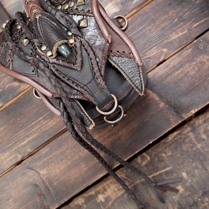 “Handcrafted tribal leather holster with braided details and green gemstone centerpiece”